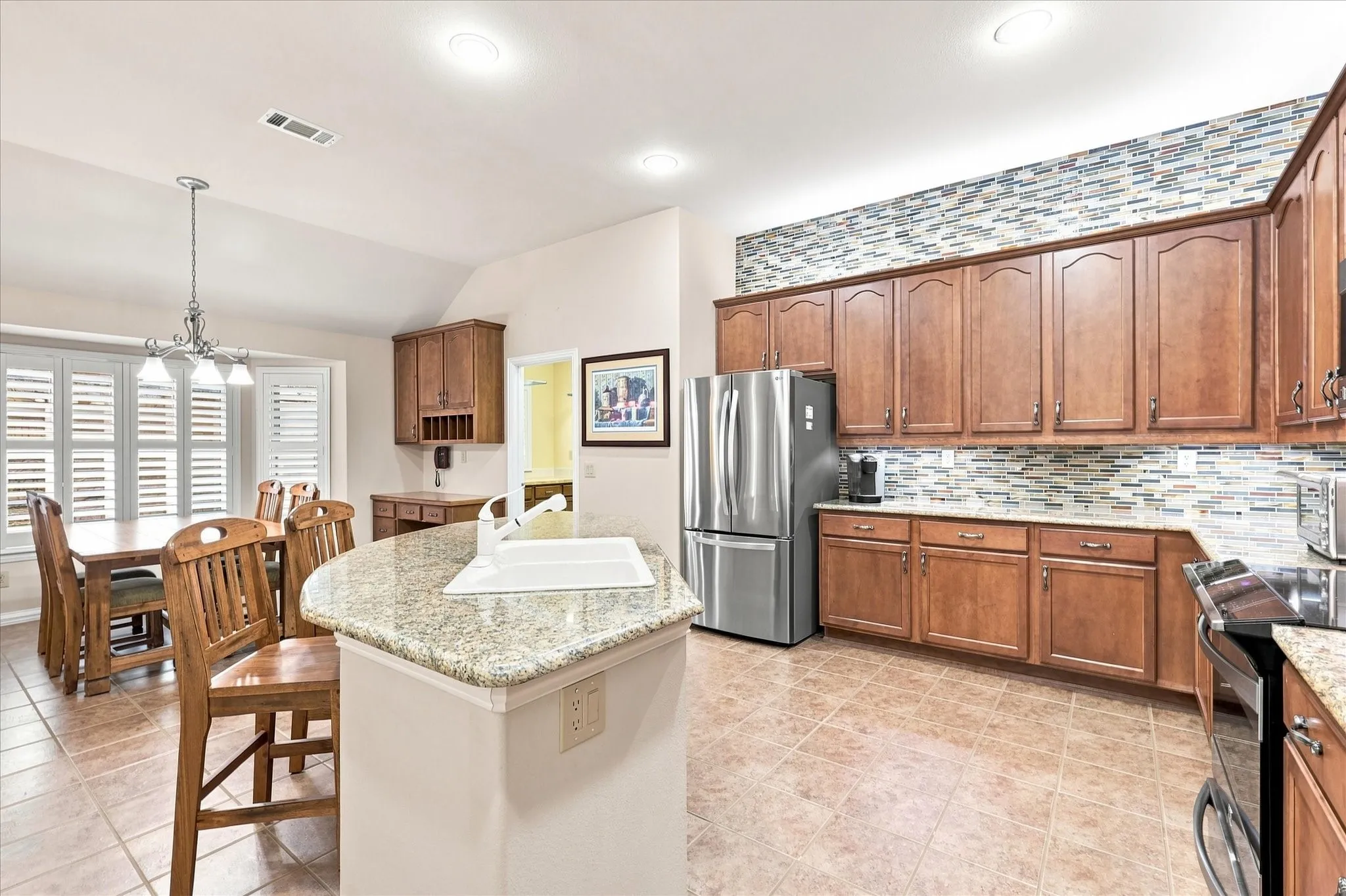 Kitchen featuring wood cabinetry, granite countertops, stainless steel refrigerator, tile flooring, and a tiled backsplash
