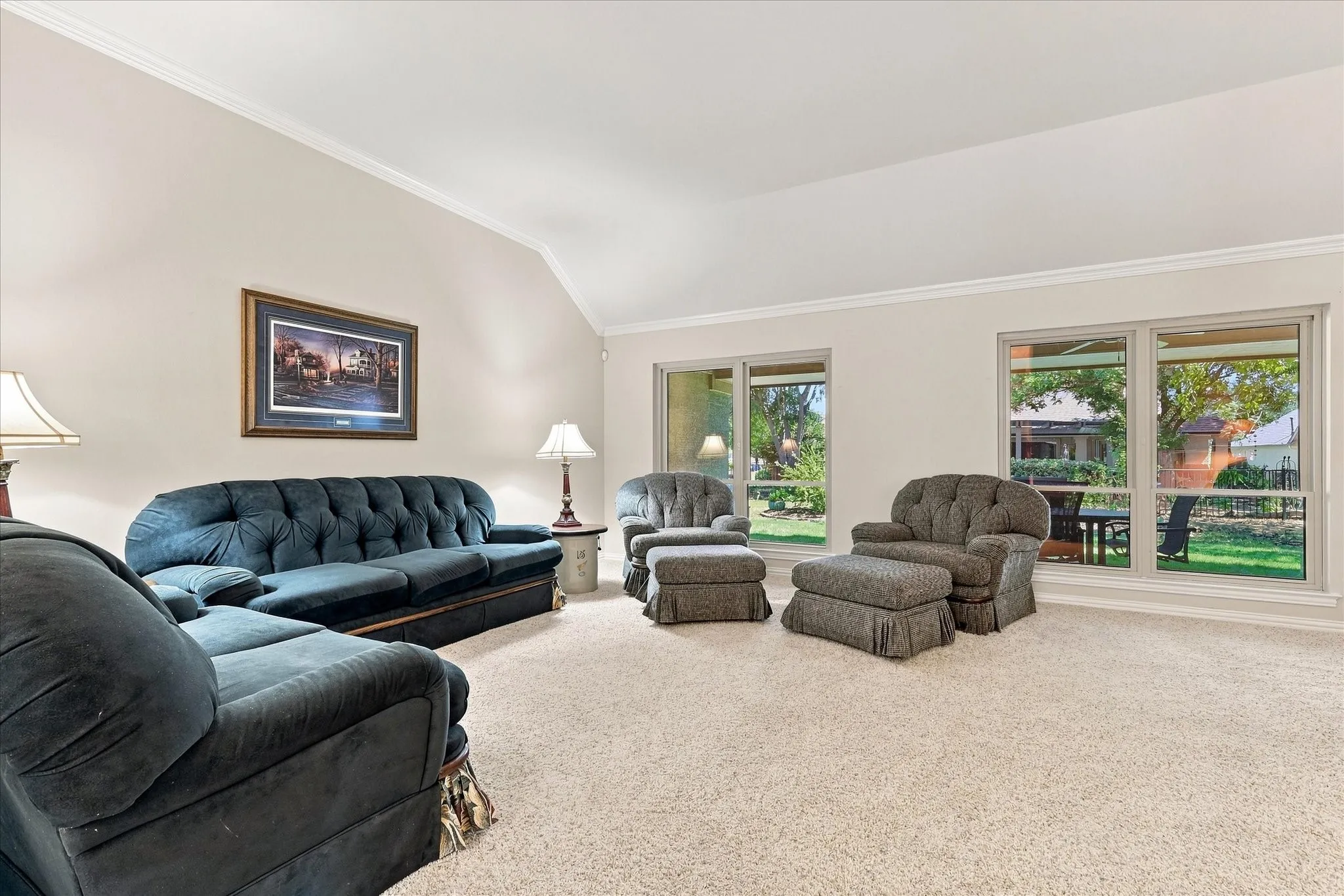 Vaulted ceiling with crown molding, expansive wall space, large windows, and carpeted flooring
