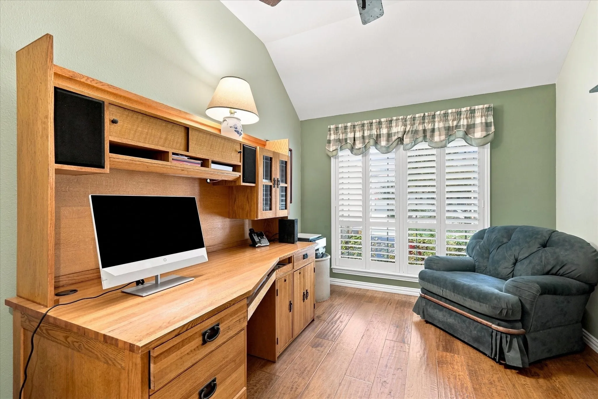 wood-finish flooring, plantation shutters, and vaulted ceiling with fan