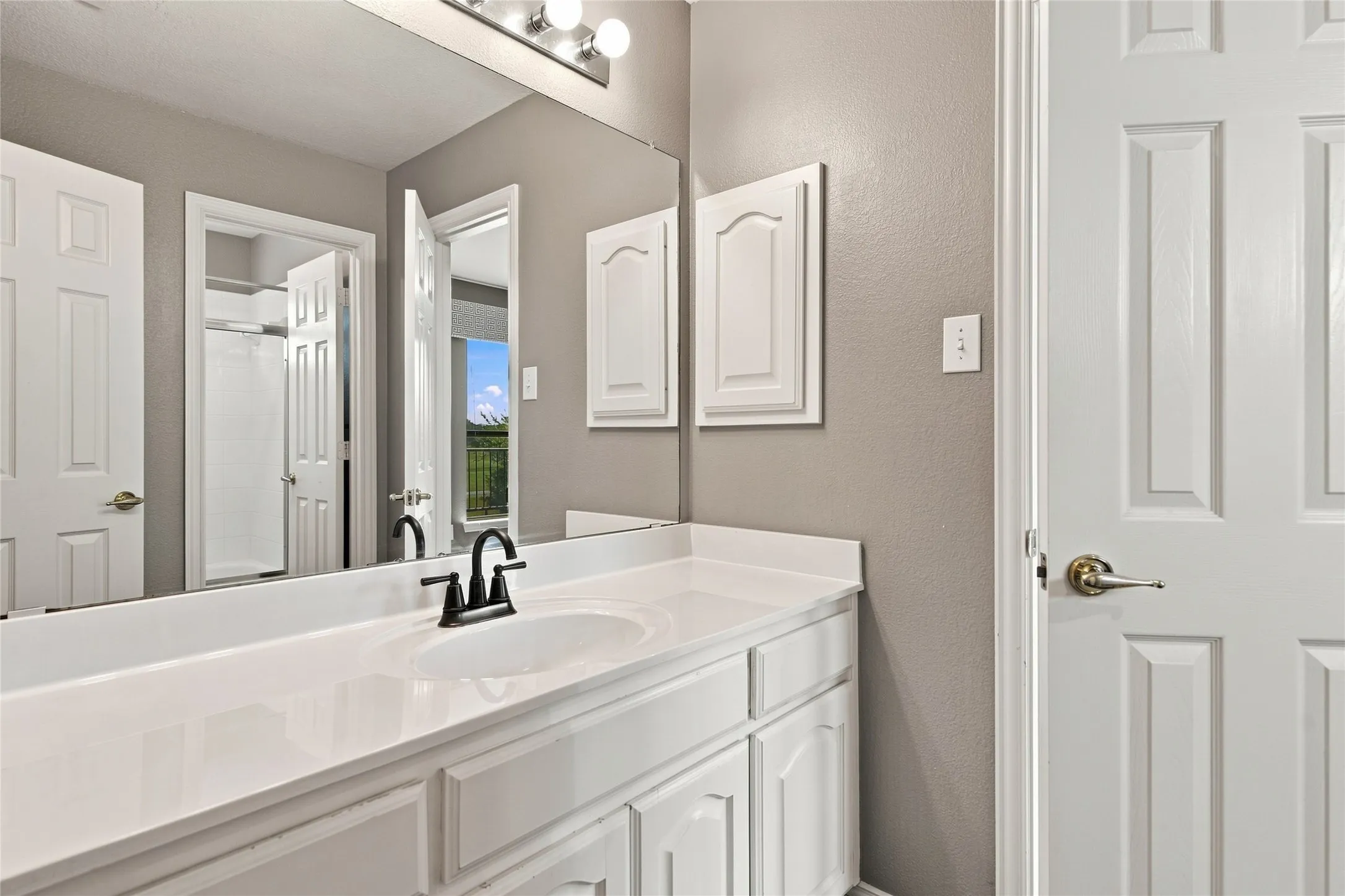 Vanity with integrated sink, white countertop, white cabinetry, and a full-width mirror.