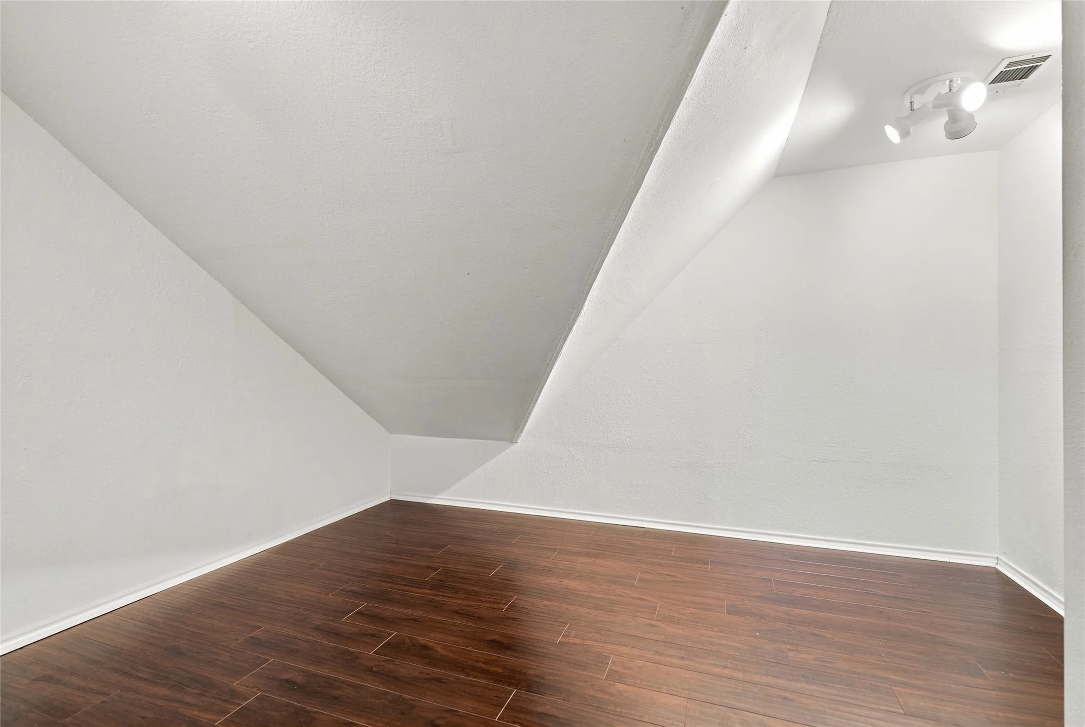 Finished bonus room with white wall finishes, lighting, and ventilation.