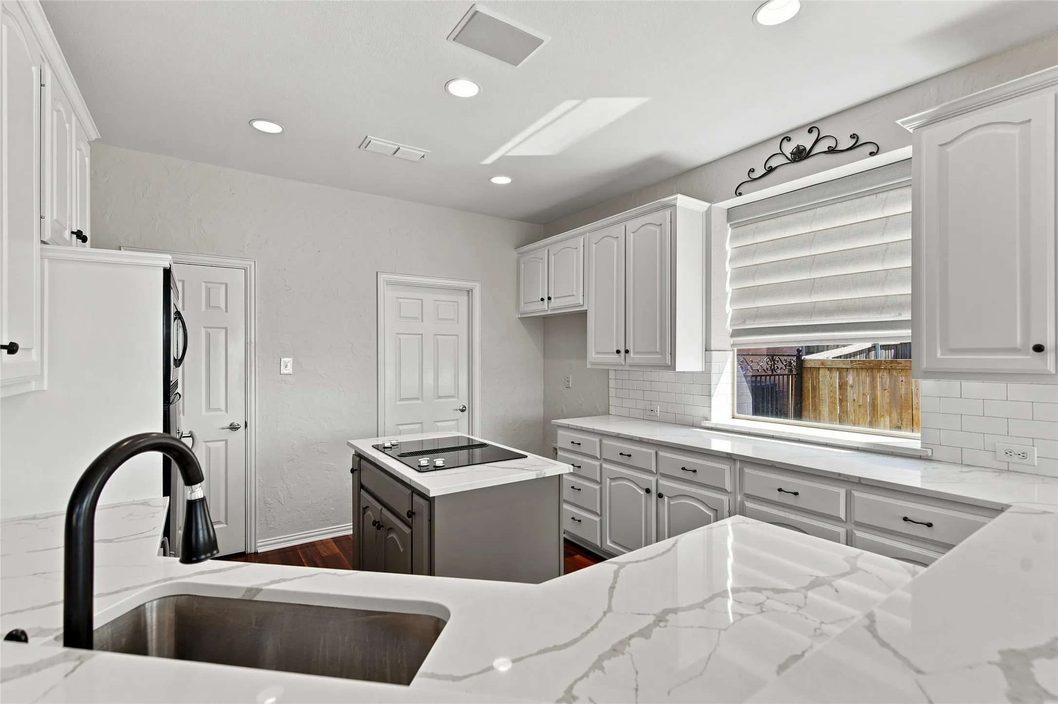 Kitchen featuring white cabinetry, quartz countertops, and a stainless steel sink with a matte black faucet.