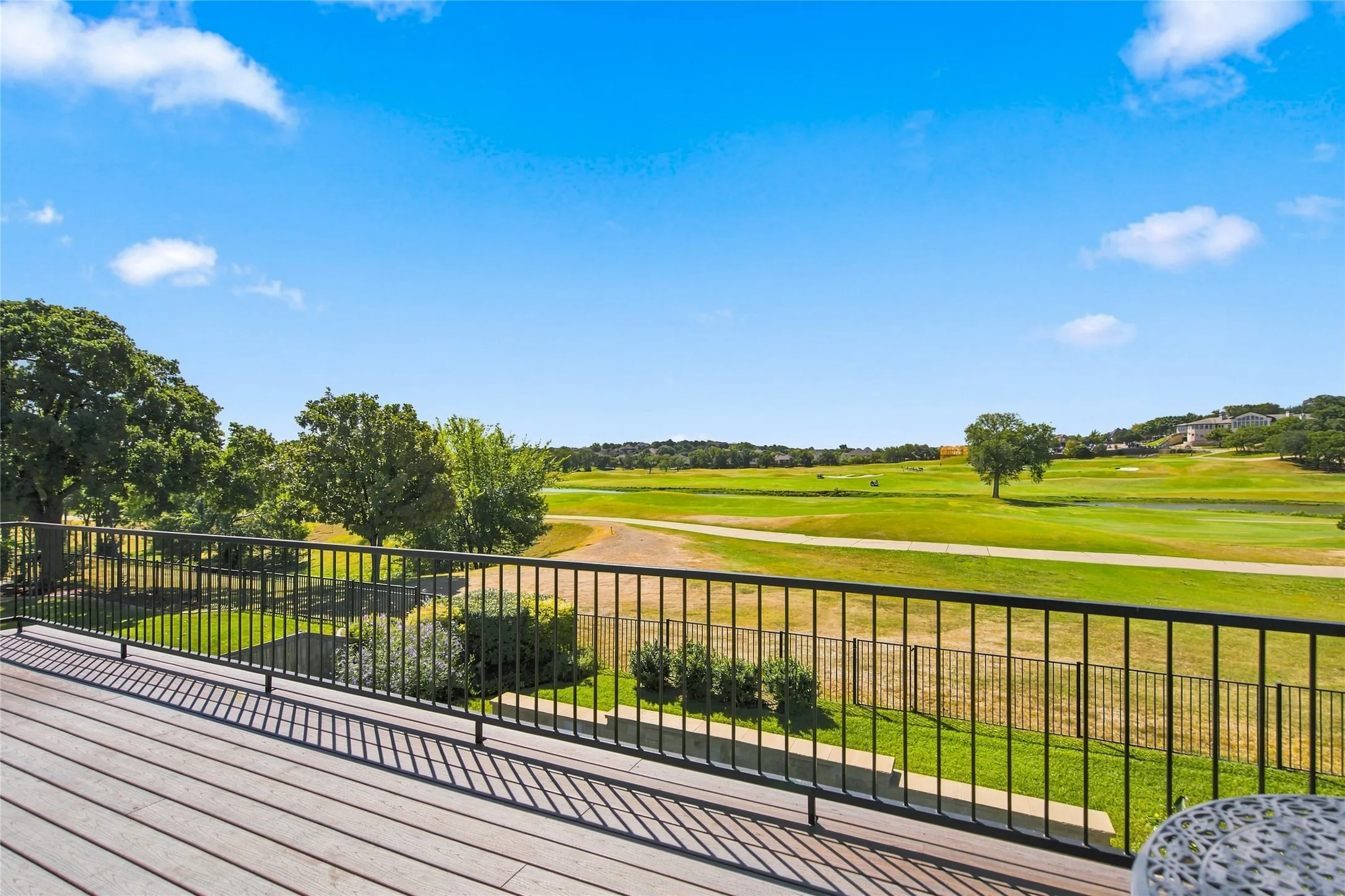 Beautiful view from spacious outdoor 2nd floor balcony with Trex decking and black metal railings, overlooking the 15th hole of Sky Creek Ranch Golf Course