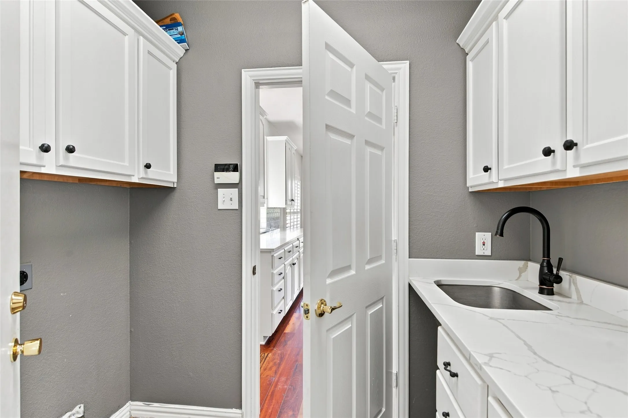 White shaker-style cabinetry with black hardware, white quartz countertop with integrated sink, and black faucet.