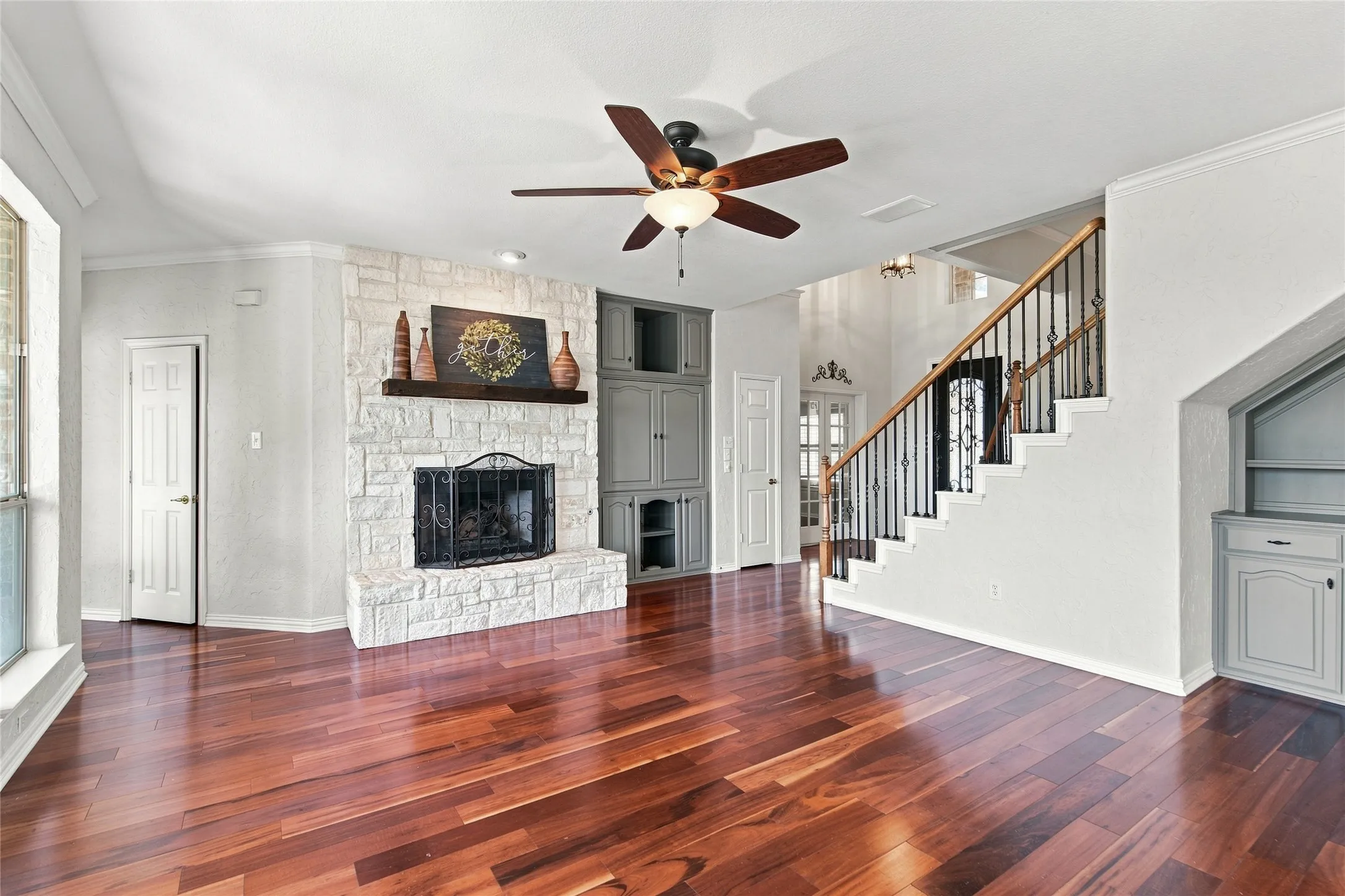 Stone fireplace with wood mantel and built-in cabinetry in living room.