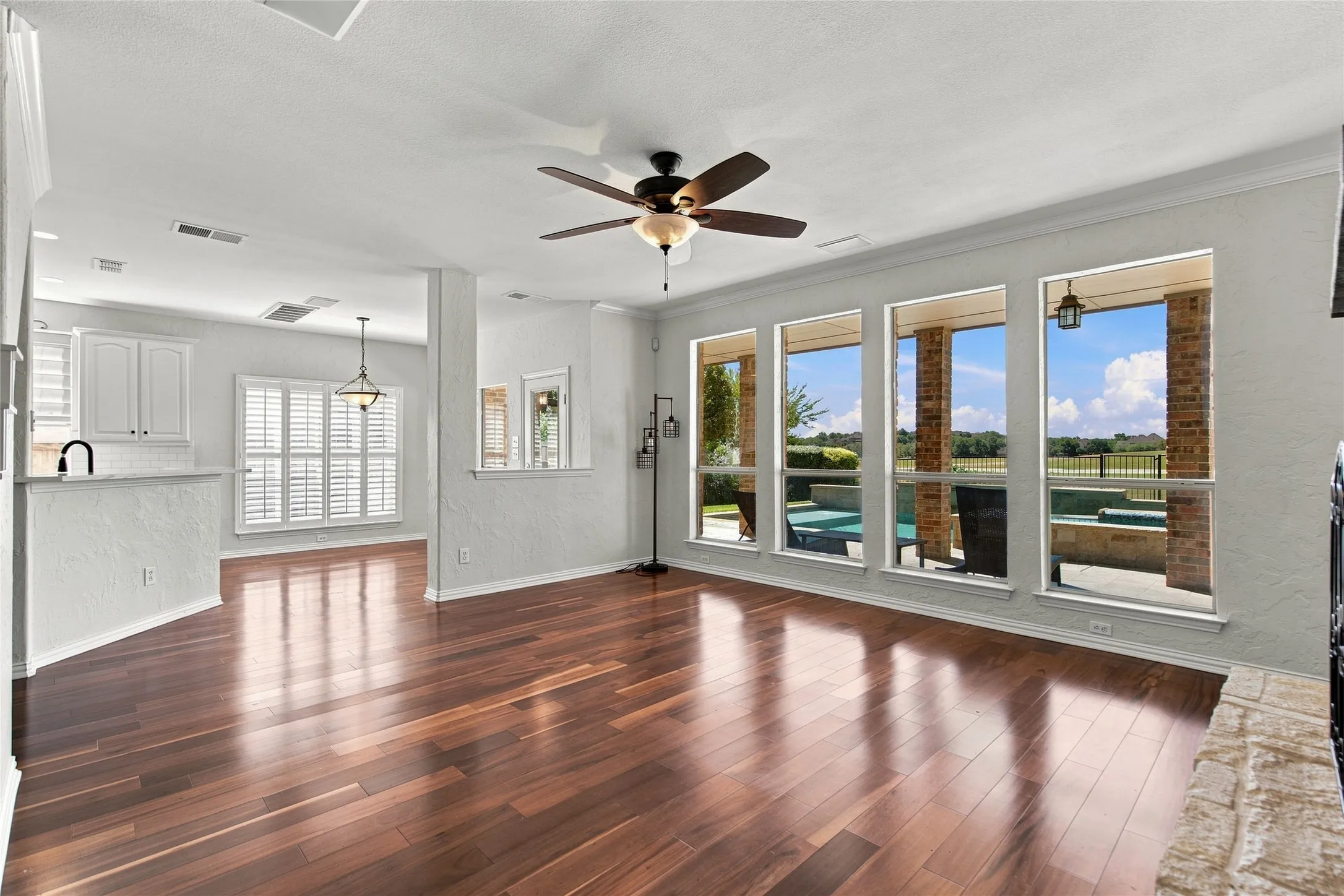 Hardwood-finish flooring, ceiling fan, white cabinetry, built-in breakfast bar, and multiple large windows overlooking golf course and resort style backyard.