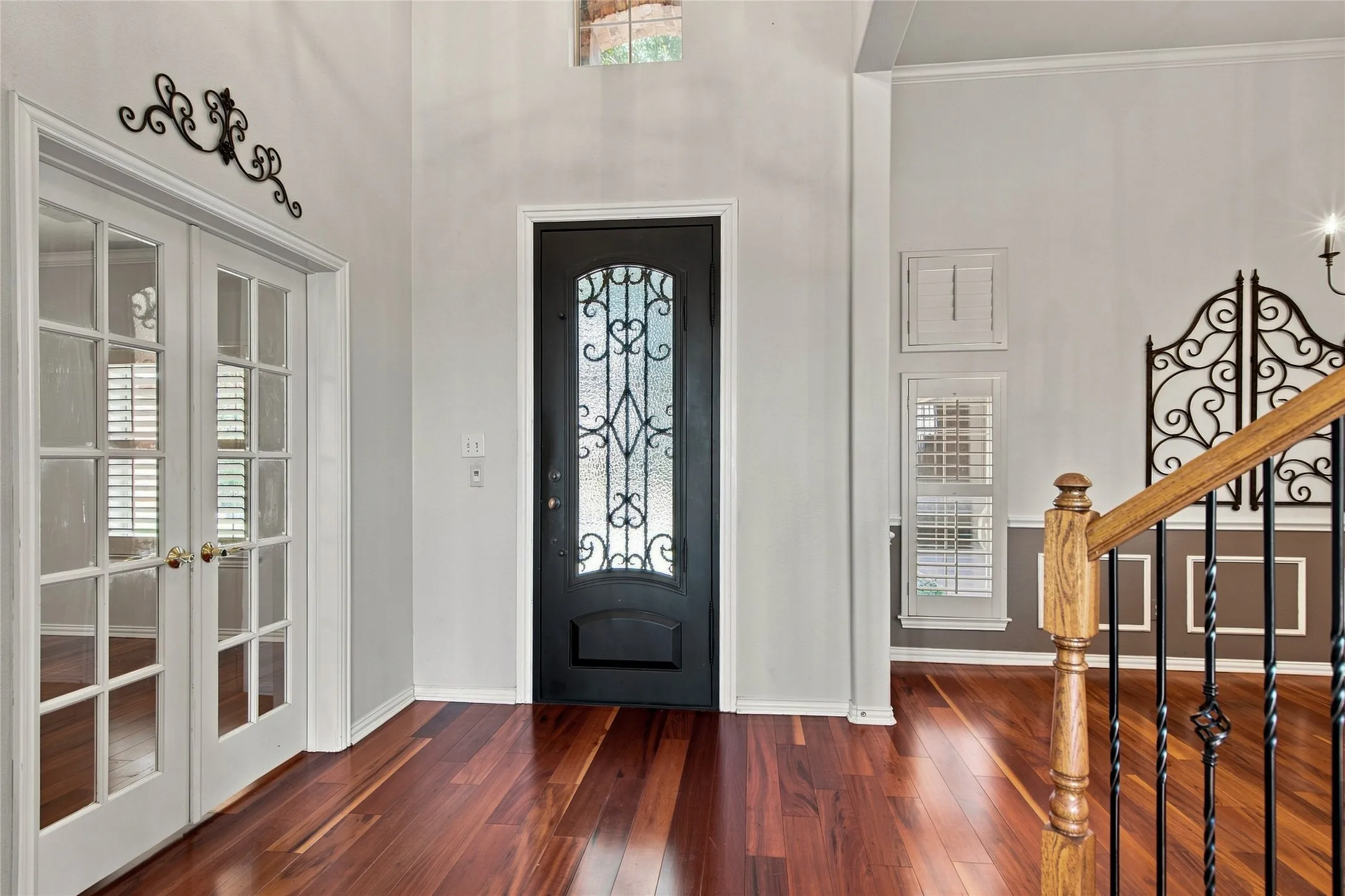 Hardwood flooring, decorative glass entry door, French doors with glass panes, dining room and wooden staircase with iron balusters