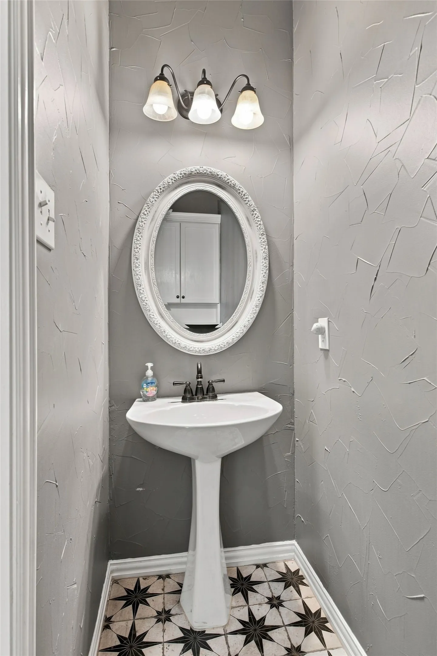 Downstairs guest bathroom with pedestal sink with dark-toned fixtures.