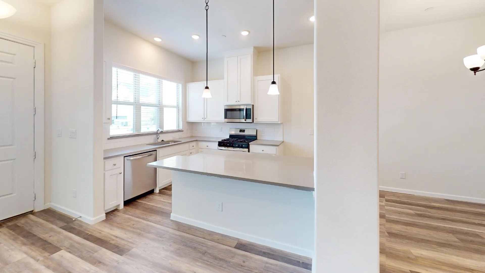 Kitchen featuring white cabinetry, stainless steel appliances, a center island with a light-toned countertop, and wood-finish flooring