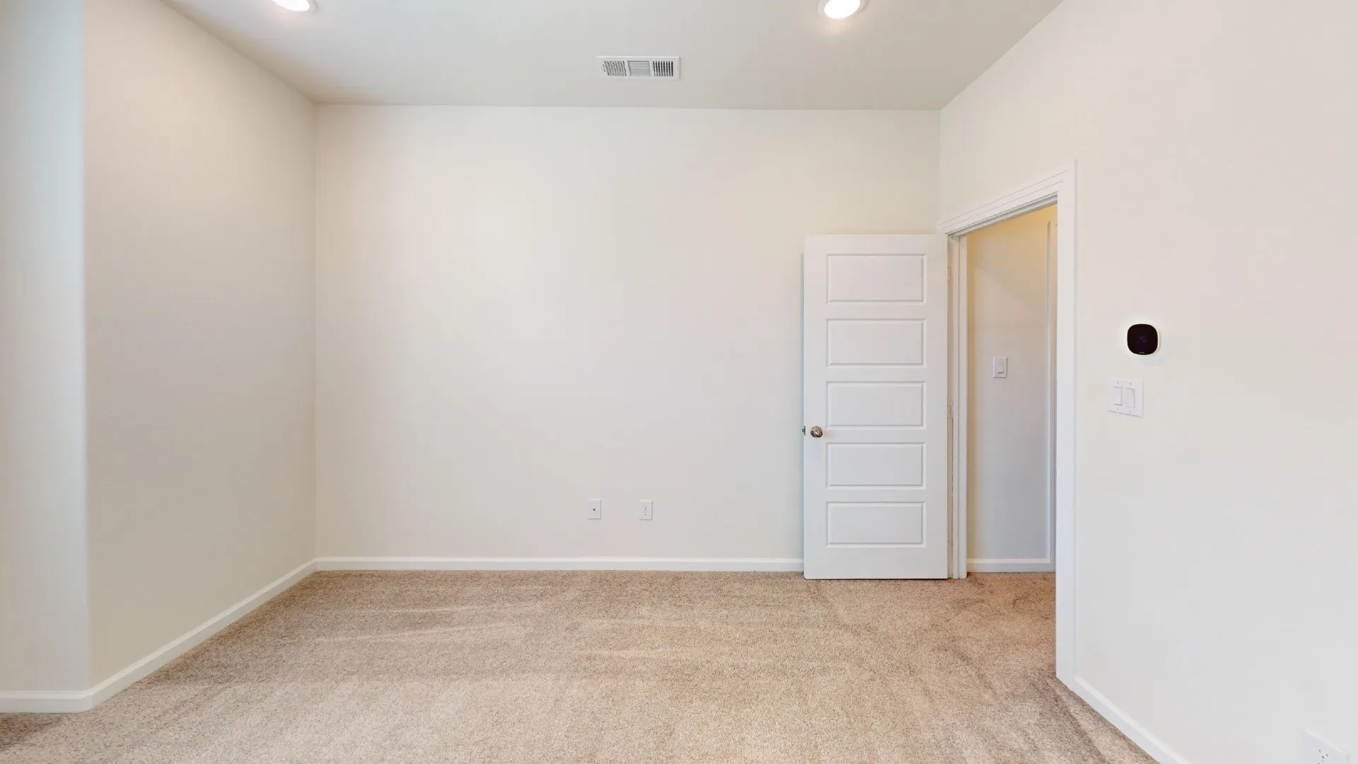 Recessed lighting illuminates neutral carpeting and light-toned walls