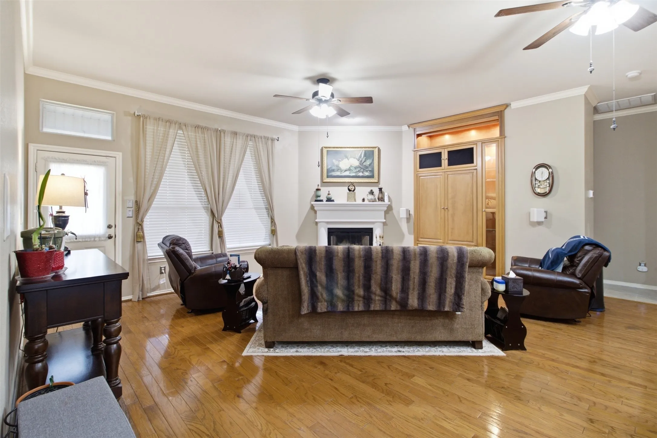 Hardwood flooring throughout, a central fireplace with mantle, built-in cabinetry, and multiple ceiling fans