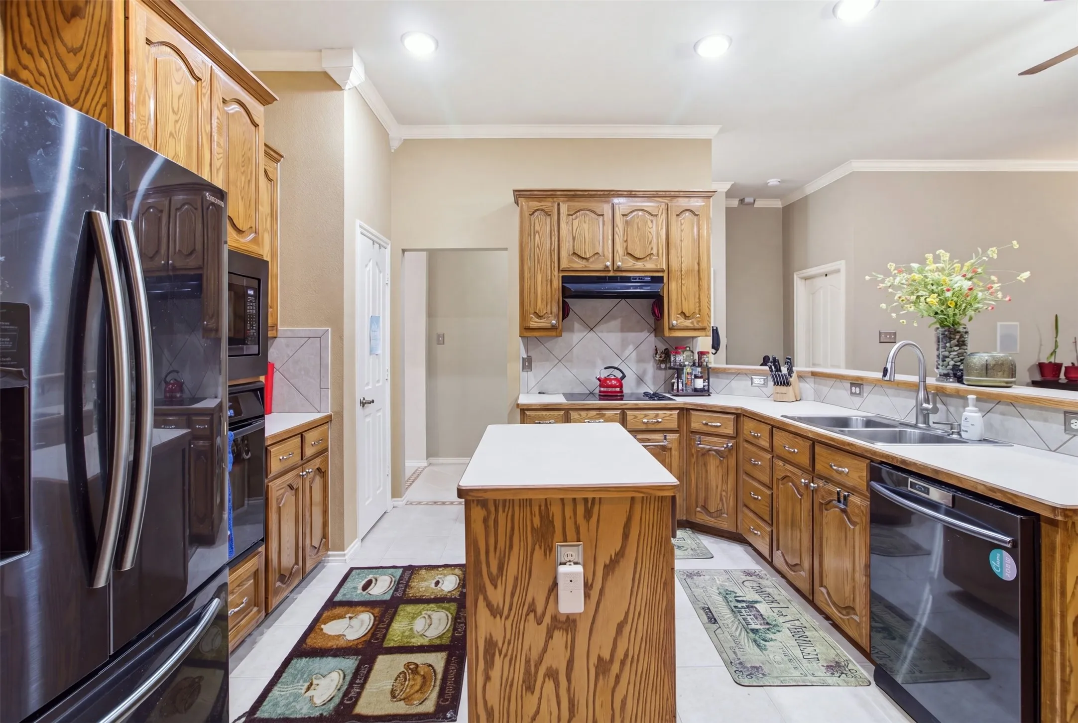 Kitchen featuring wood-finish cabinetry, white countertops, a stainless steel sink, and a built-in oven