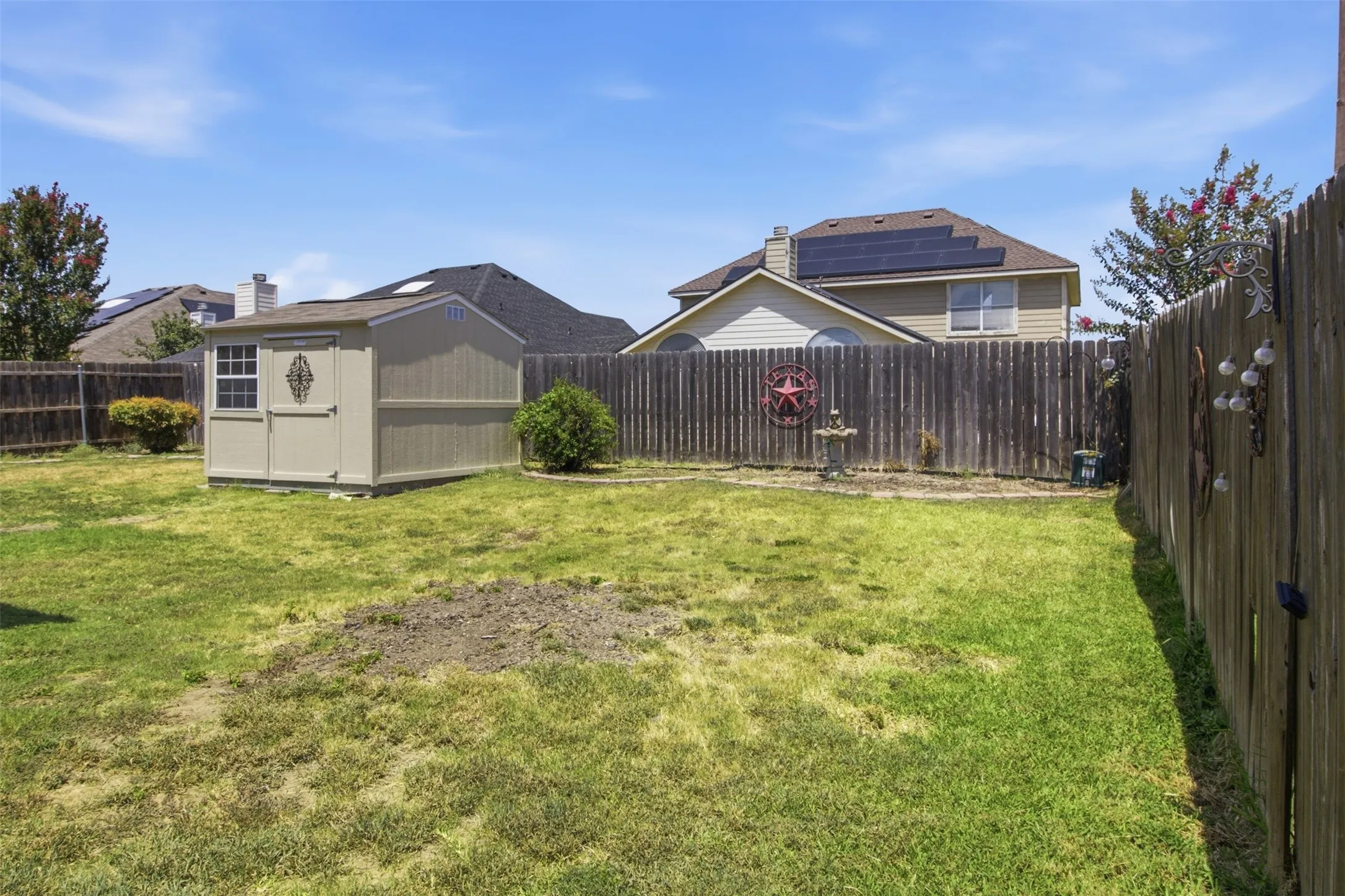 Expansive backyard featuring a wood-panel fence and a detached storage shed with a single window