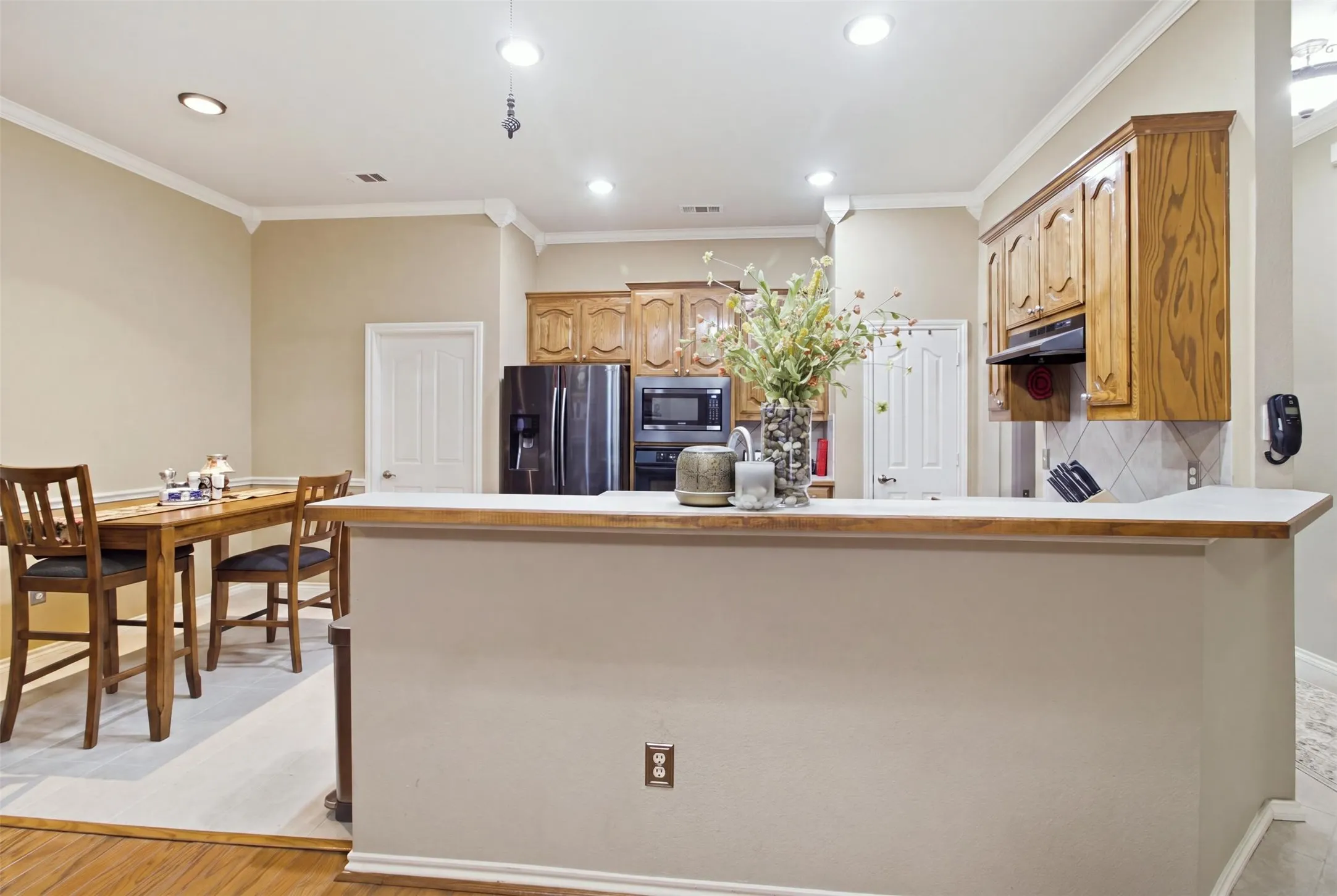 Kitchen featuring wood cabinetry, integrated appliances, and a breakfast bar