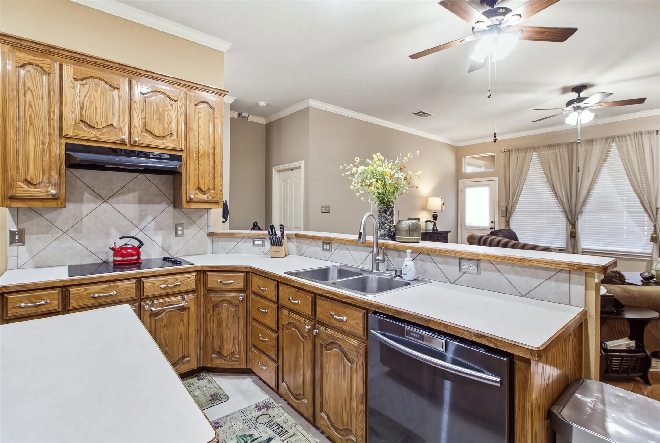 Kitchen featuring wood cabinetry, white countertops, a tile backsplash, and stainless steel appliances