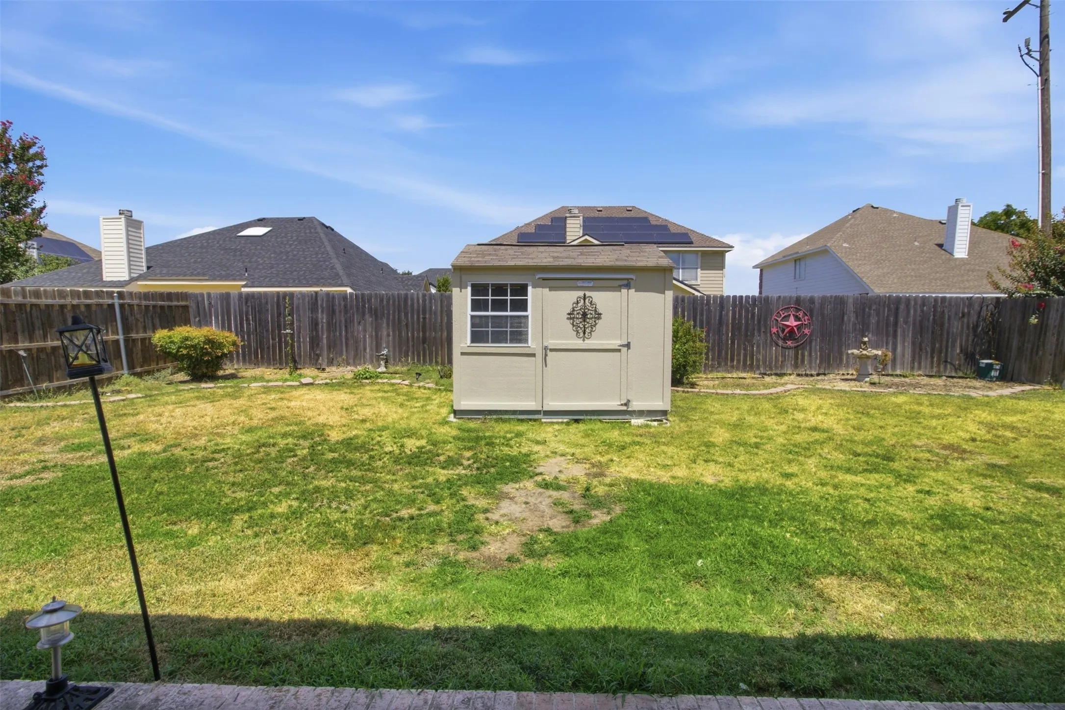 Backyard featuring a wooden privacy fence, a detached storage shed, and a concrete patio edge