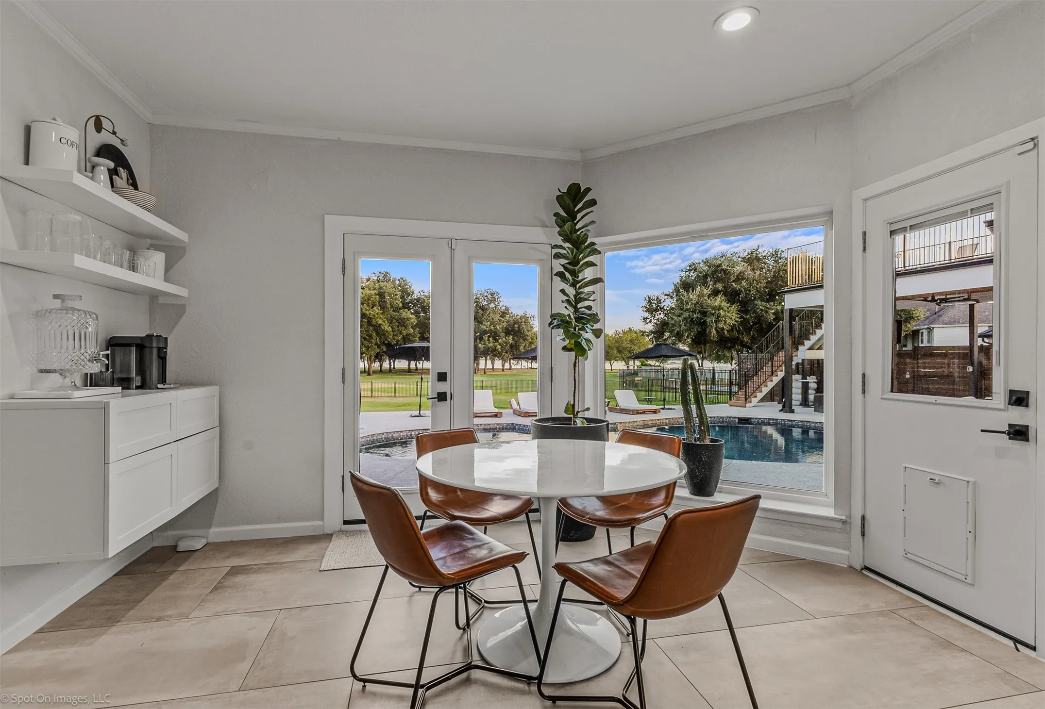 Built-in floating cabinetry with open shelving, tile flooring, corner window, and double French doors opening to a swimming pool