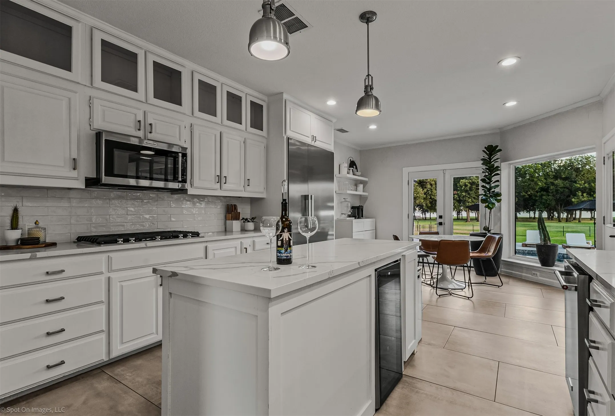 Kitchen featuring white cabinetry, stainless steel appliances, a center island with integrated beverage cooler, and light-colored tile flooring
