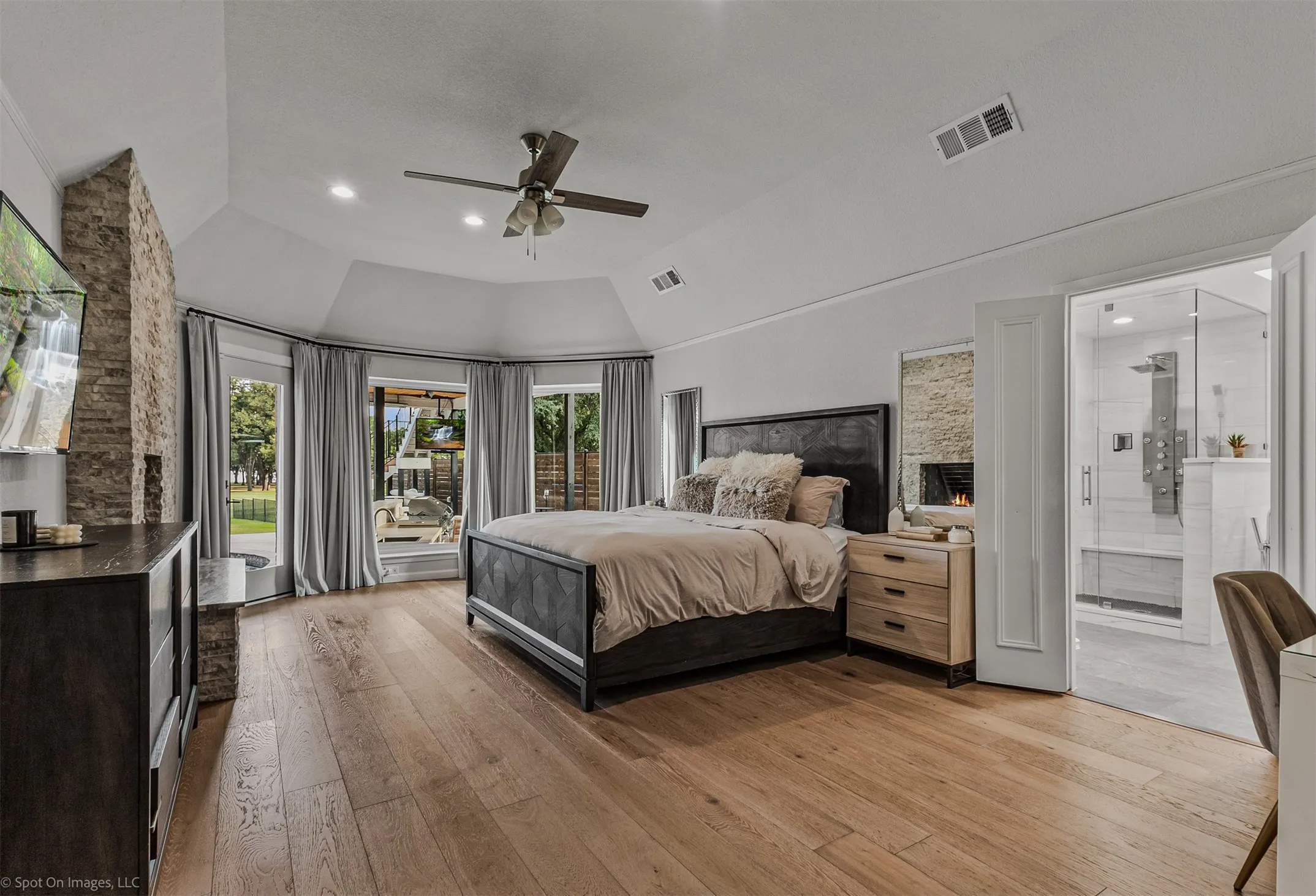 Wood-finish flooring, vaulted ceiling, recessed lighting, ceiling fan, and a built-in fireplace with stone surround