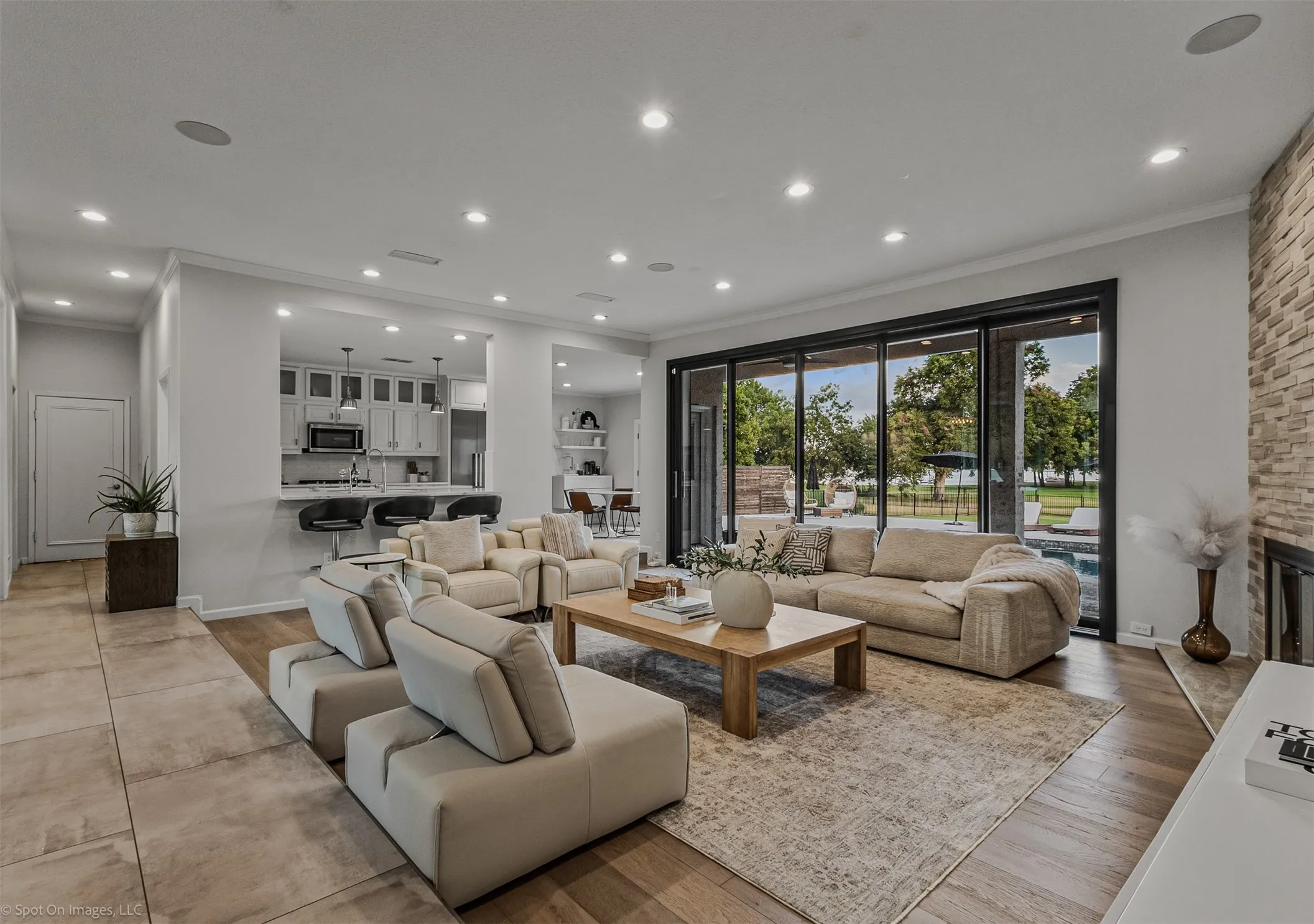 Spacious living area with wood-finish flooring, a stone accent wall, and recessed lighting