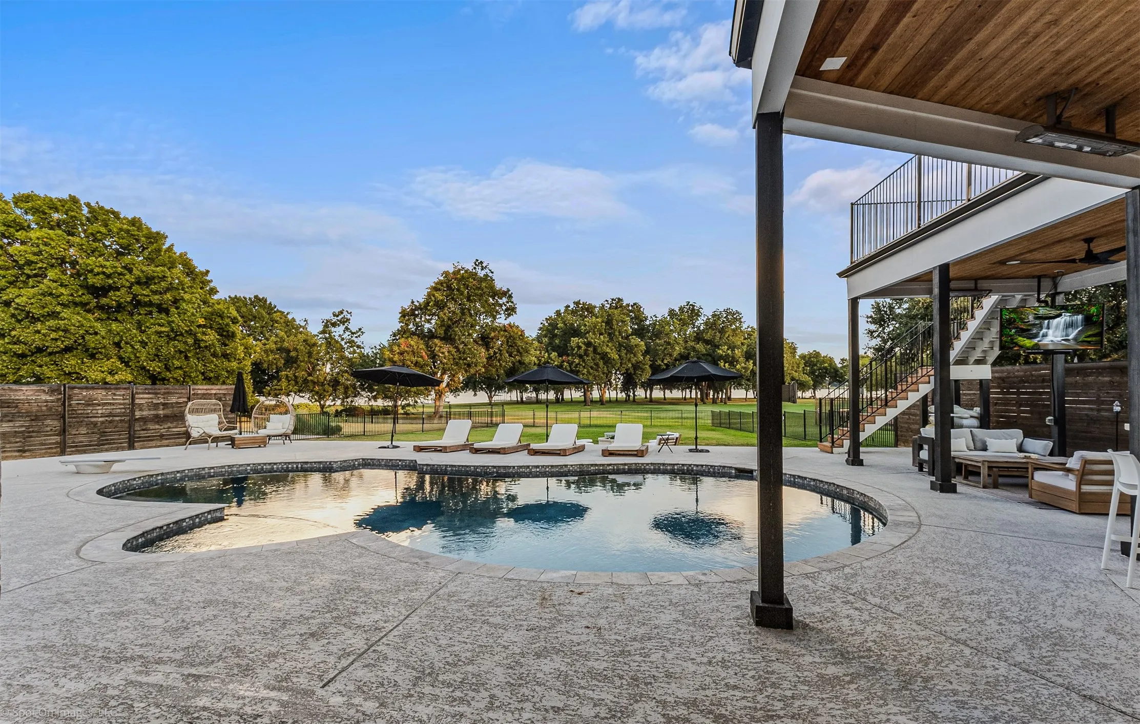 Custom-shaped swimming pool with textured concrete decking