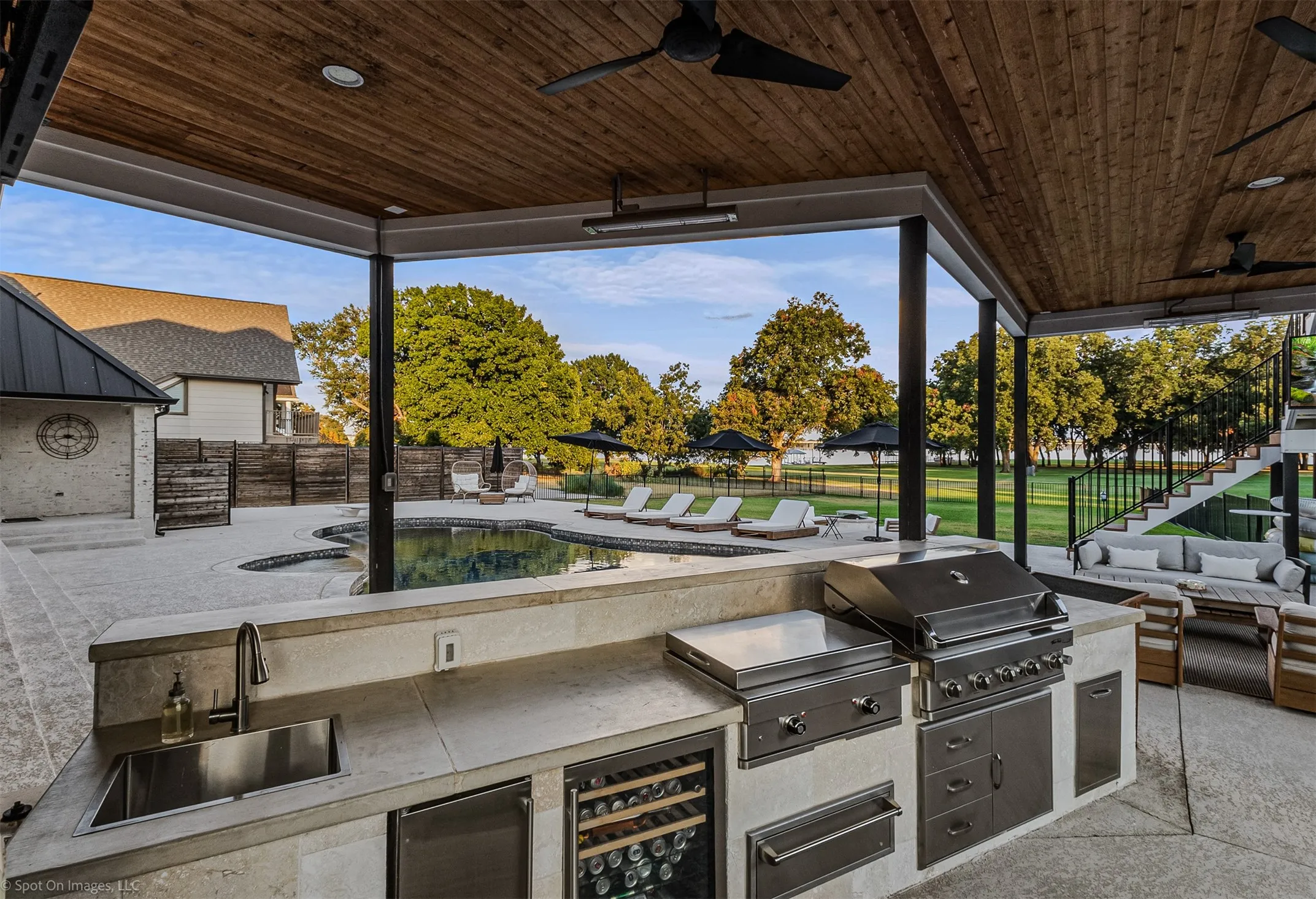 Covered outdoor kitchen featuring a built-in grill, integrated sink, and wine refrigerator
