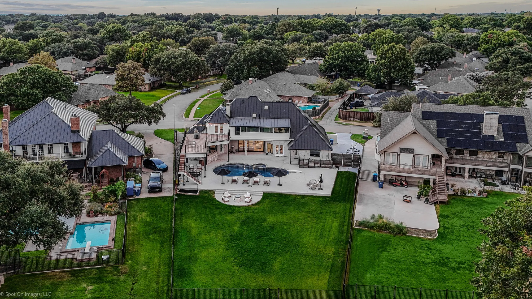 Contemporary residence featuring a private pool with expansive decking, a large manicured lawn, and multiple outdoor patios