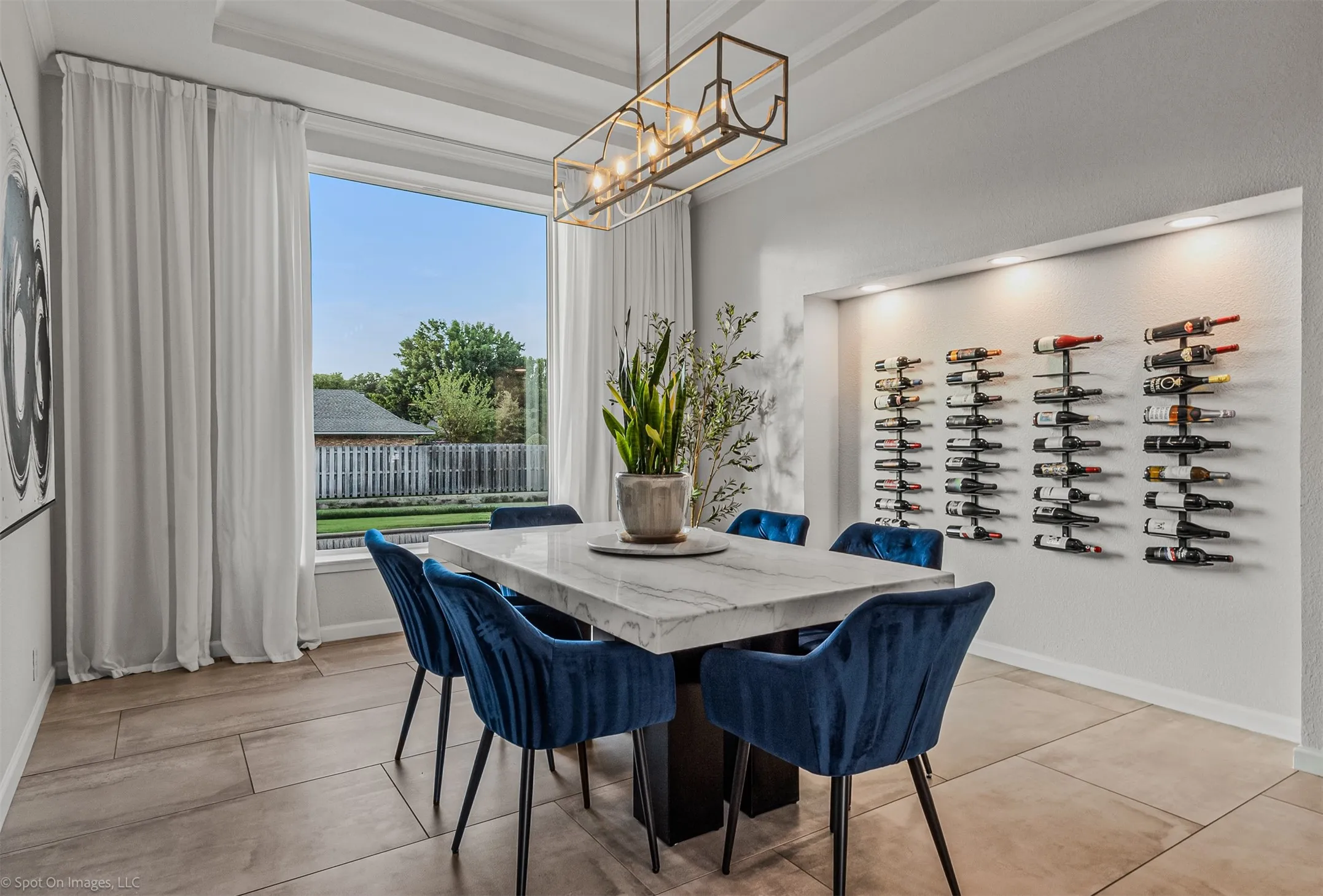 Tray ceiling with a linear chandelier, built-in wine storage with accent lighting, large picture window, and wide-plank tile flooring