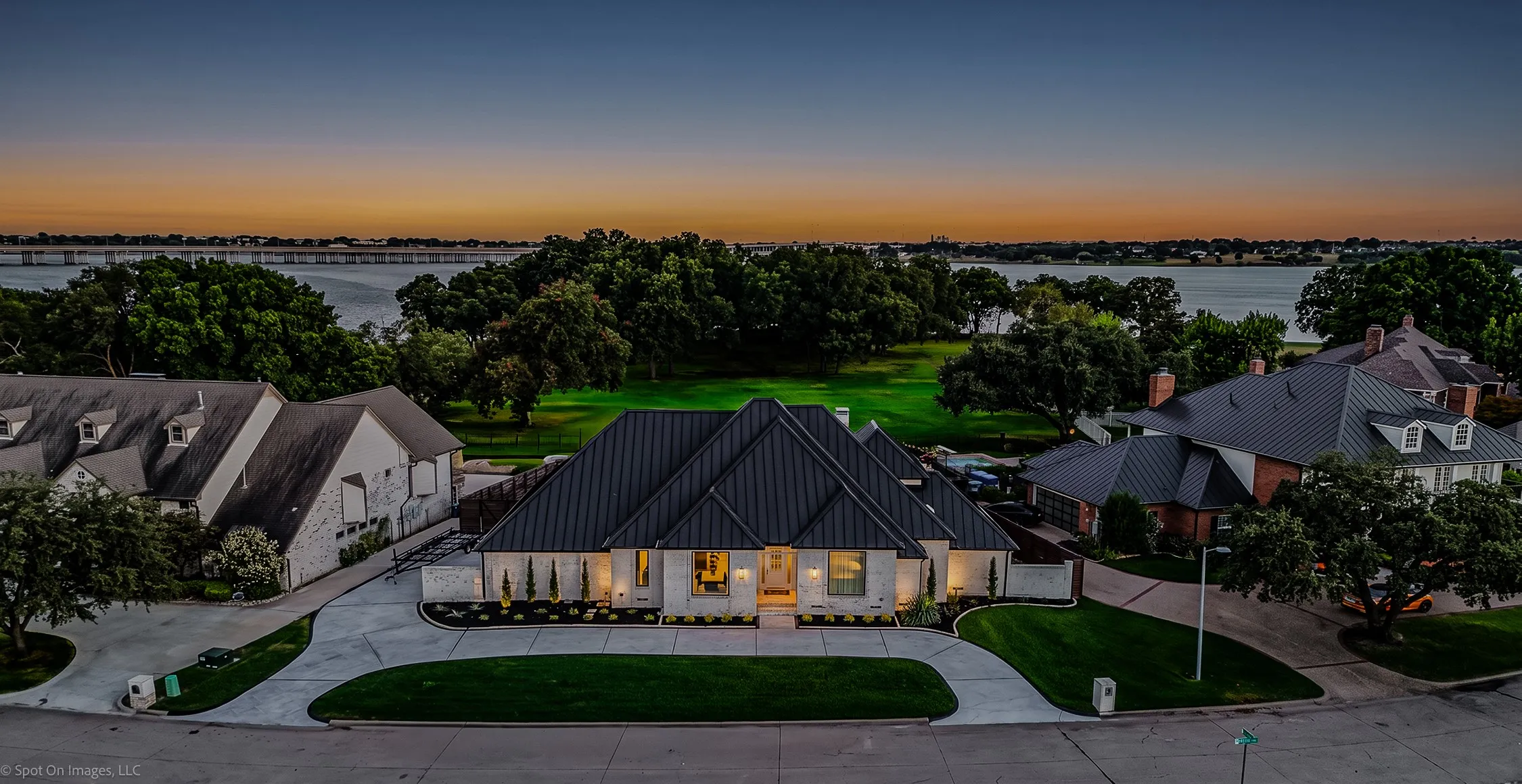 Modern architecture featuring a dark metal roof, light-colored stone facade, and a curved driveway