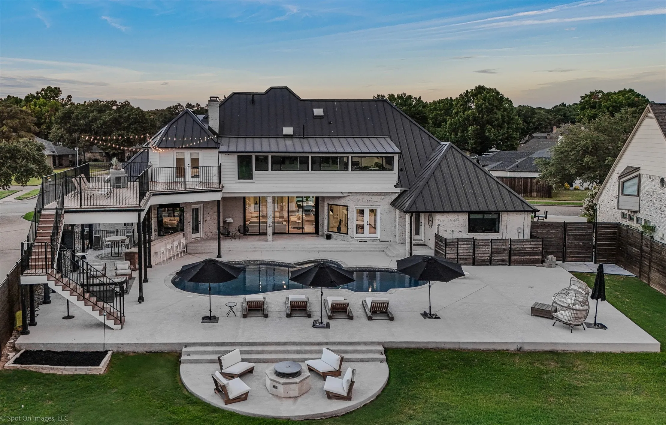 Resort-style backyard featuring a dark-bottom swimming pool, extensive concrete patio, and a dedicated fire pit area