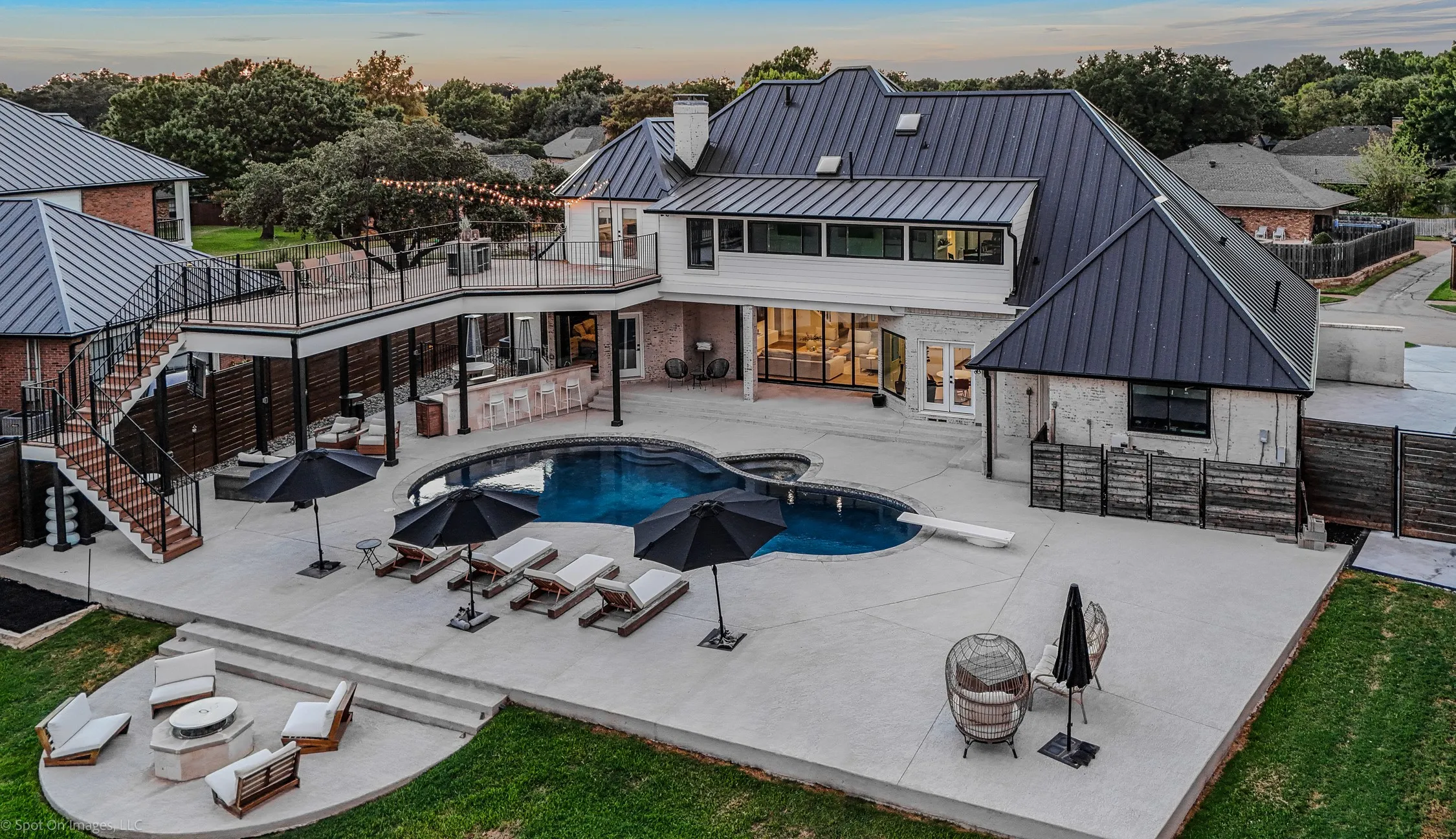 Expansive backyard featuring a custom pool, tiered concrete patio, and a dedicated fire pit area