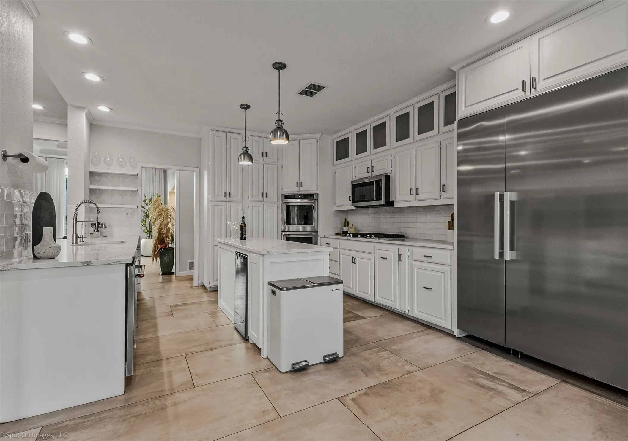 Spacious kitchen featuring white cabinetry, stainless steel appliances, a large center island, tile flooring, and recessed lighting