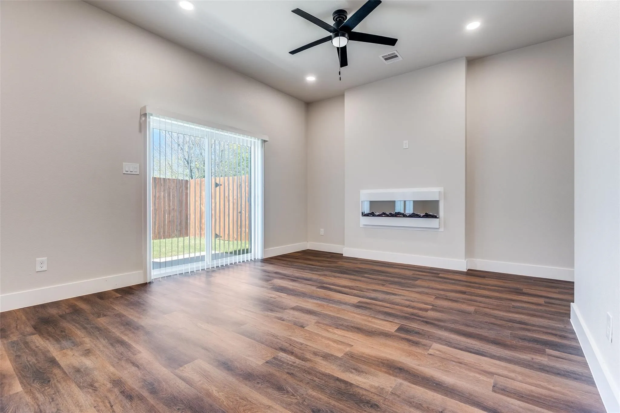Wood-finish flooring, recessed lighting, and a built-in wall fireplace