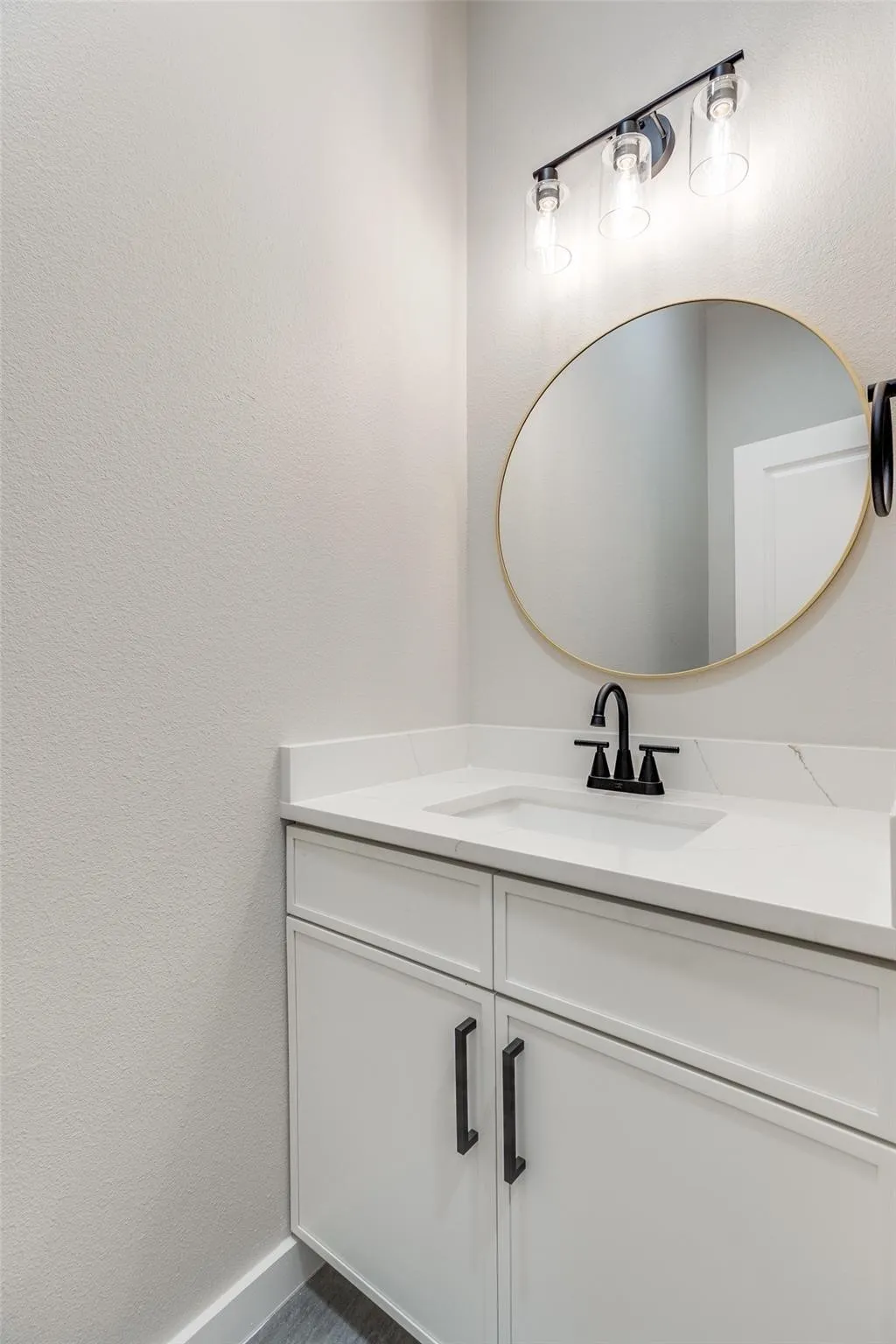 White vanity with a single basin sink, matte black faucet, and white countertop
