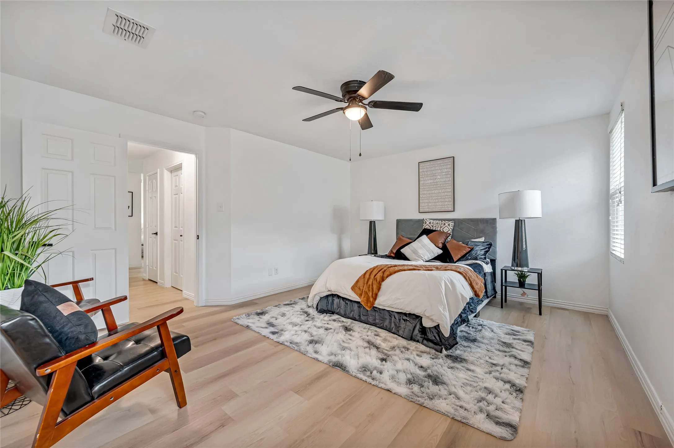 Spacious room featuring light wood-finish flooring, a ceiling fan with integrated lighting, and white paneled doors