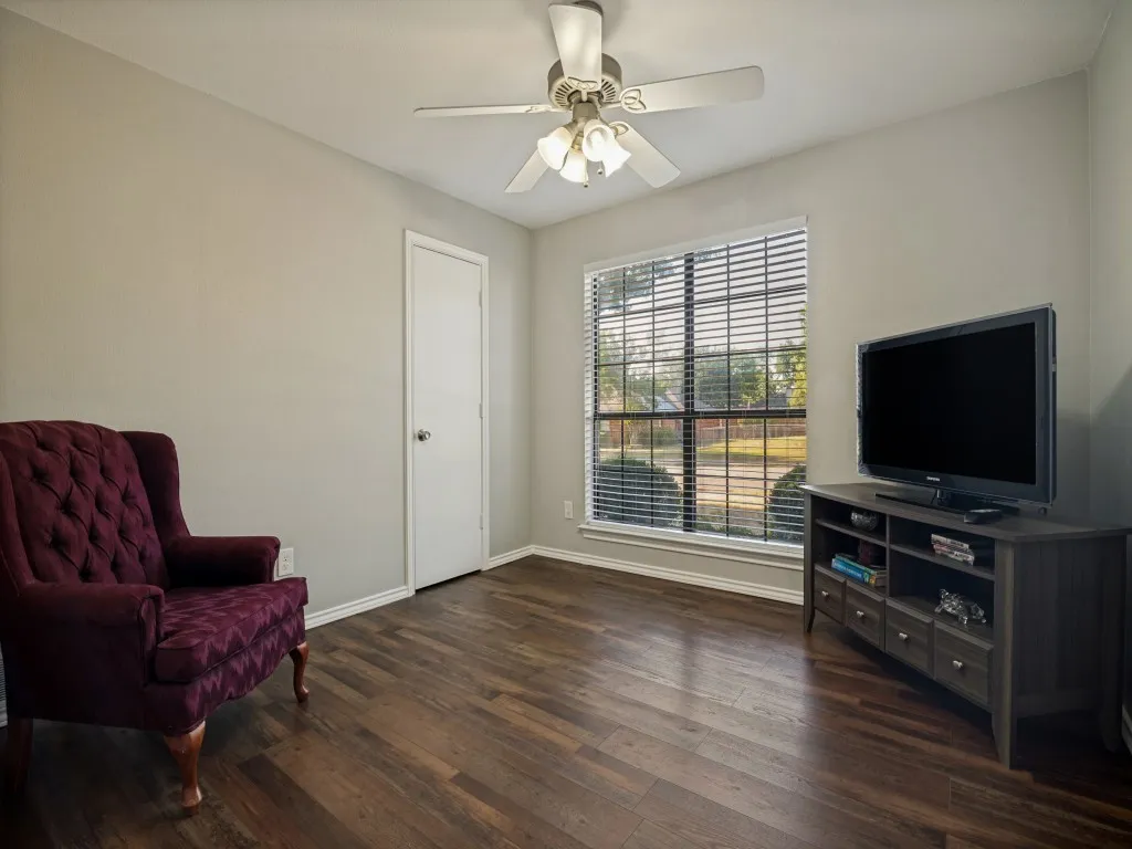Wood-finish flooring, ceiling fan with integrated lighting, window with blinds, and painted walls