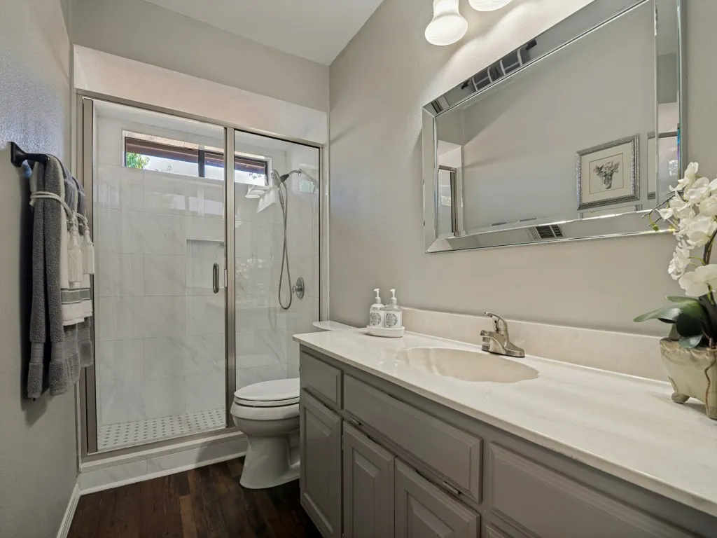 Glass-enclosed shower with white tiled walls and built-in shelving, complemented by a window for natural light