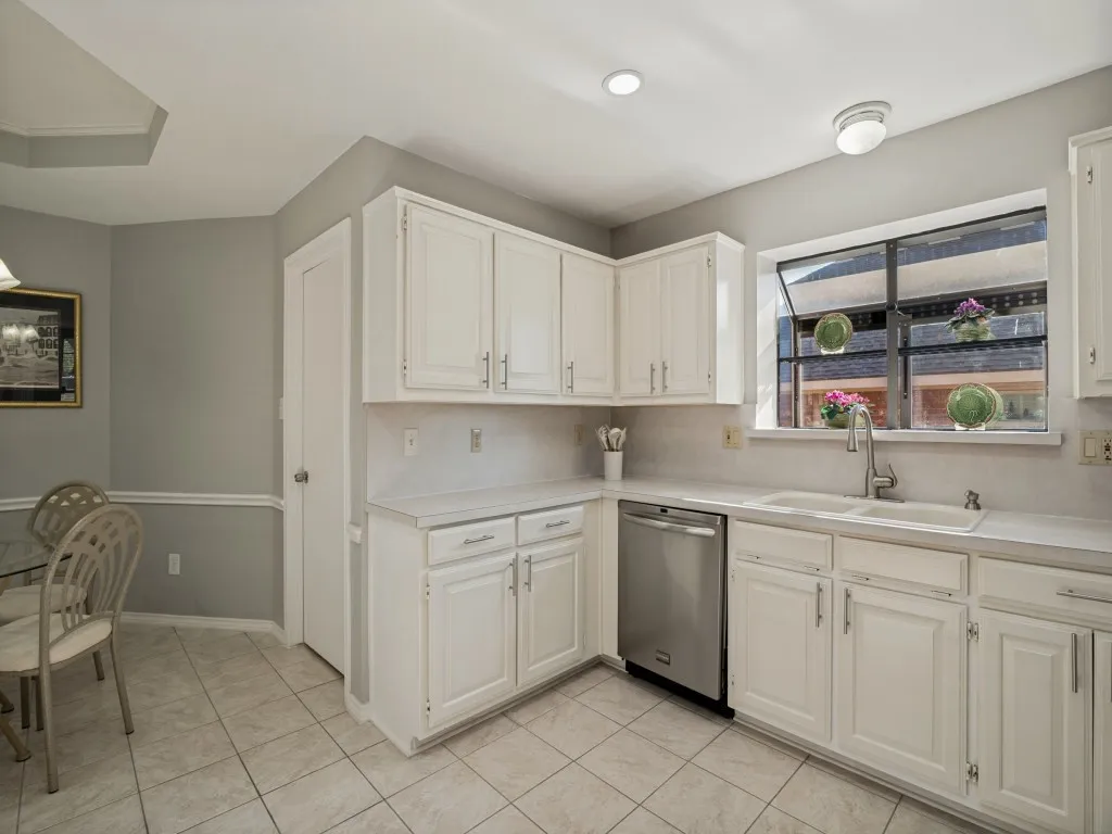 White cabinetry with modern pulls, tile flooring, stainless steel dishwasher, double basin sink, and recessed lighting