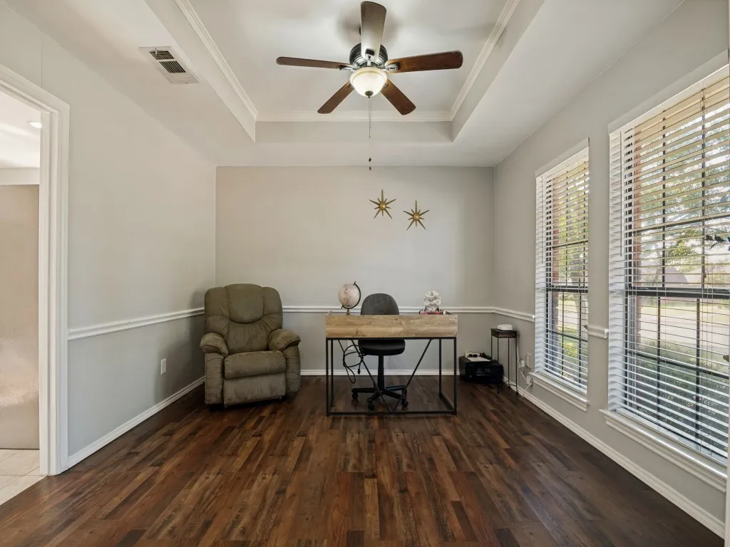 Tray ceiling with a ceiling fan, wood-finish flooring, and white trim