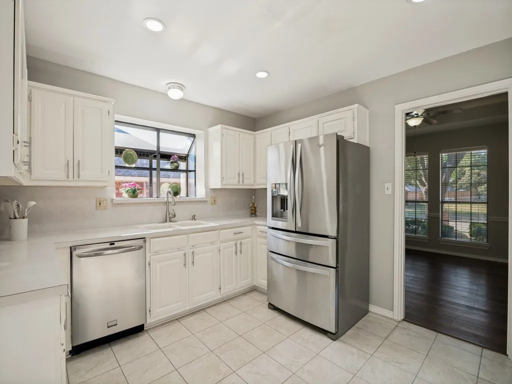 Kitchen featuring white cabinetry, light-toned countertops, a double basin sink, and stainless steel appliances