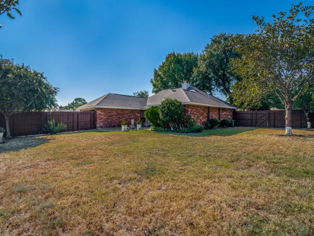 Brick exterior, fenced yard, mature trees, pitched roofline, chimney