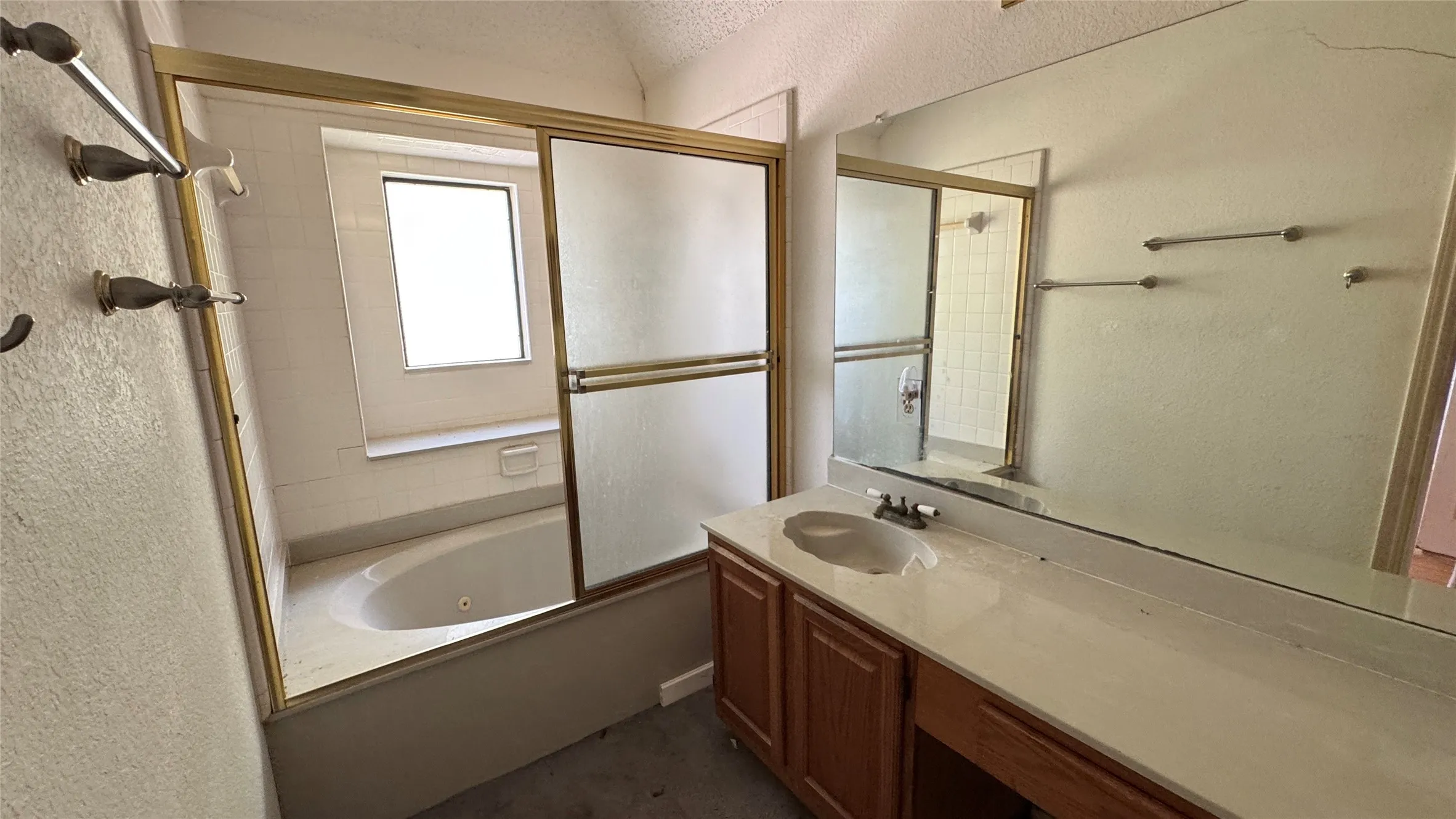 Built-in jetted tub with tile surround, framed glass shower enclosure, wood-finish vanity with integrated sink, and expansive wall-mounted mirror