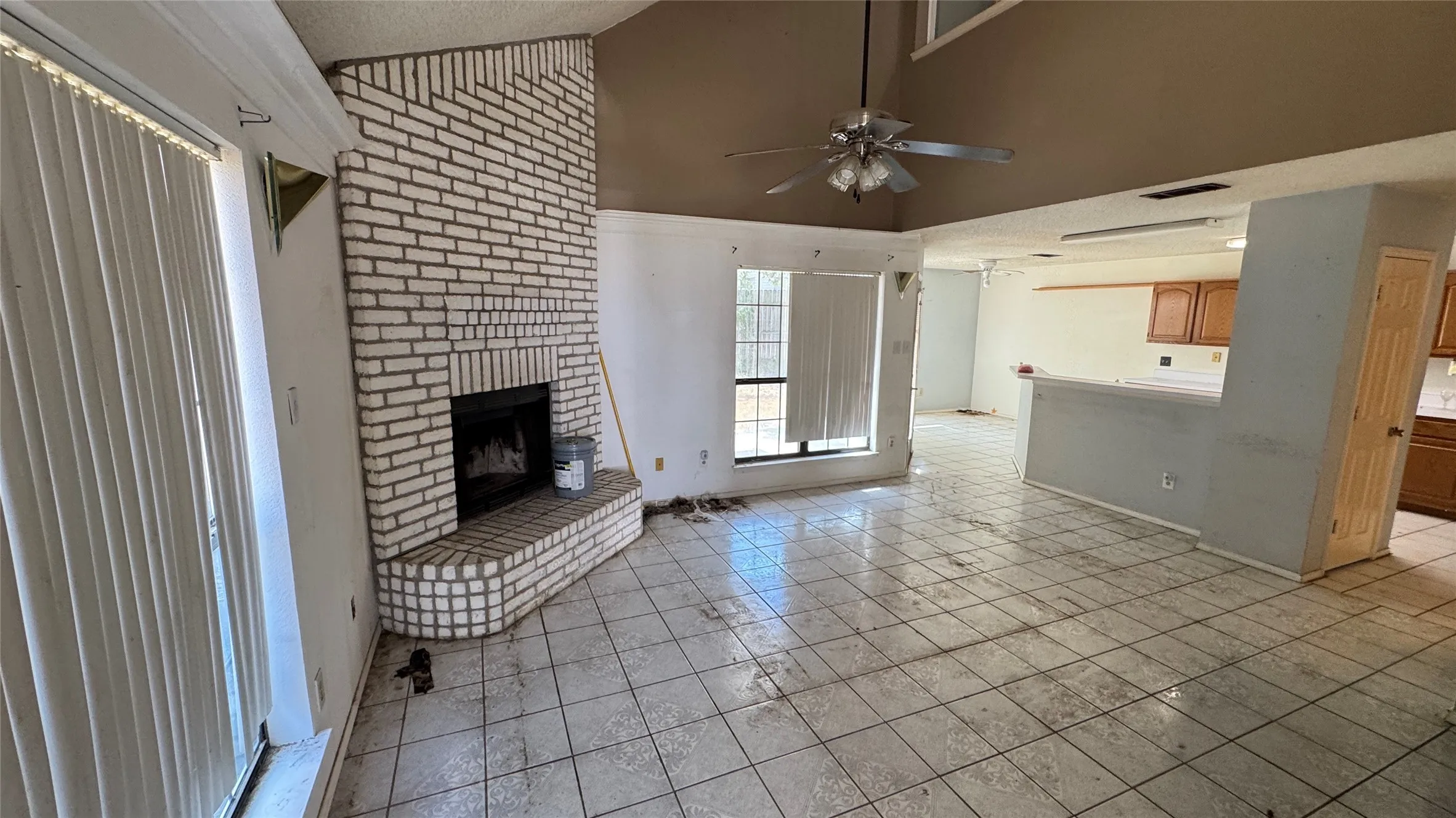 Living space with a brick fireplace, vaulted ceiling, and ceiling fan