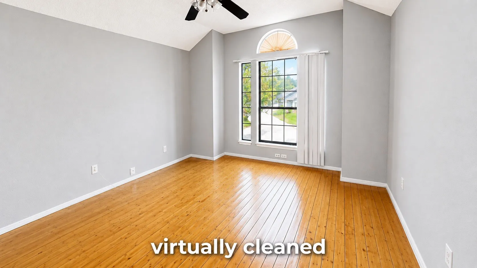 Vaulted ceiling with a ceiling fan, wood-finish flooring, and large windows with an arched transom