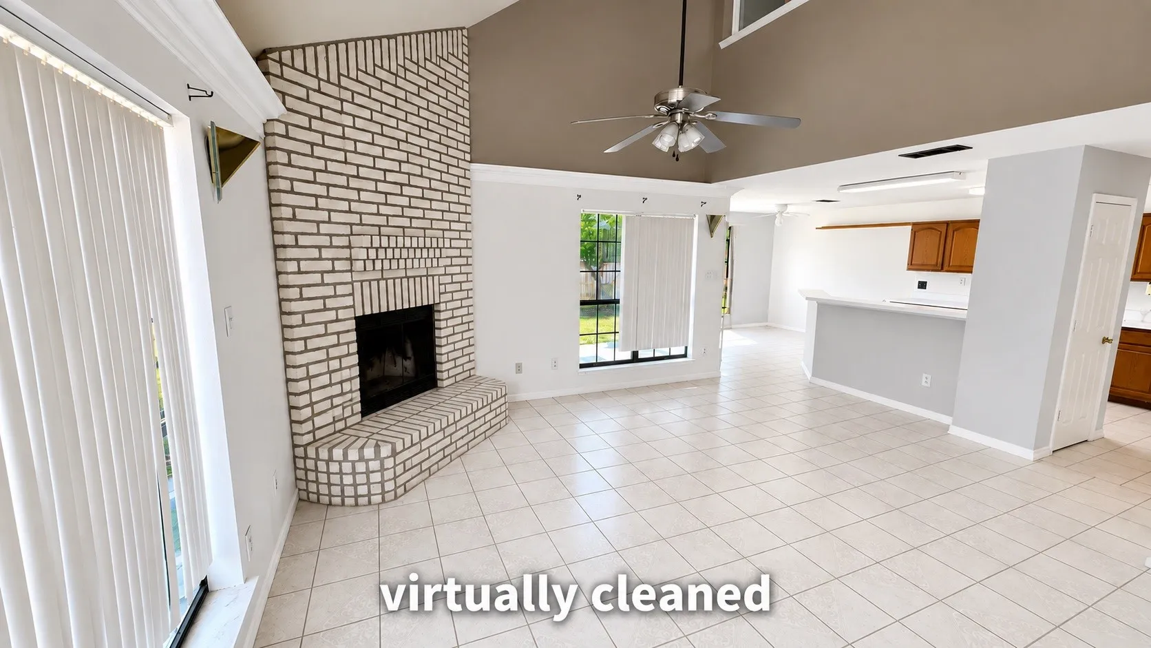 Vaulted ceiling, white brick fireplace, tile flooring, ceiling fan, and window with vertical blinds