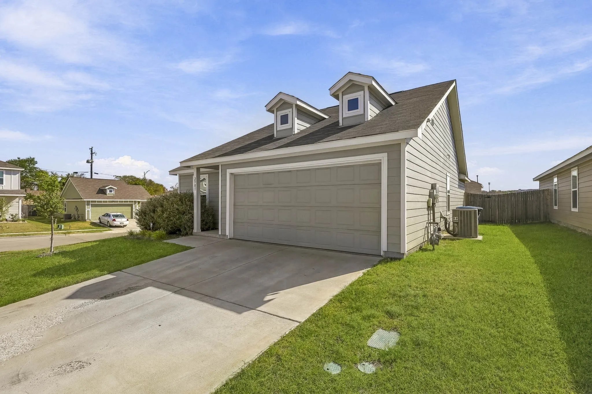 Light gray siding exterior with a dark shingle roof and two dormer windows