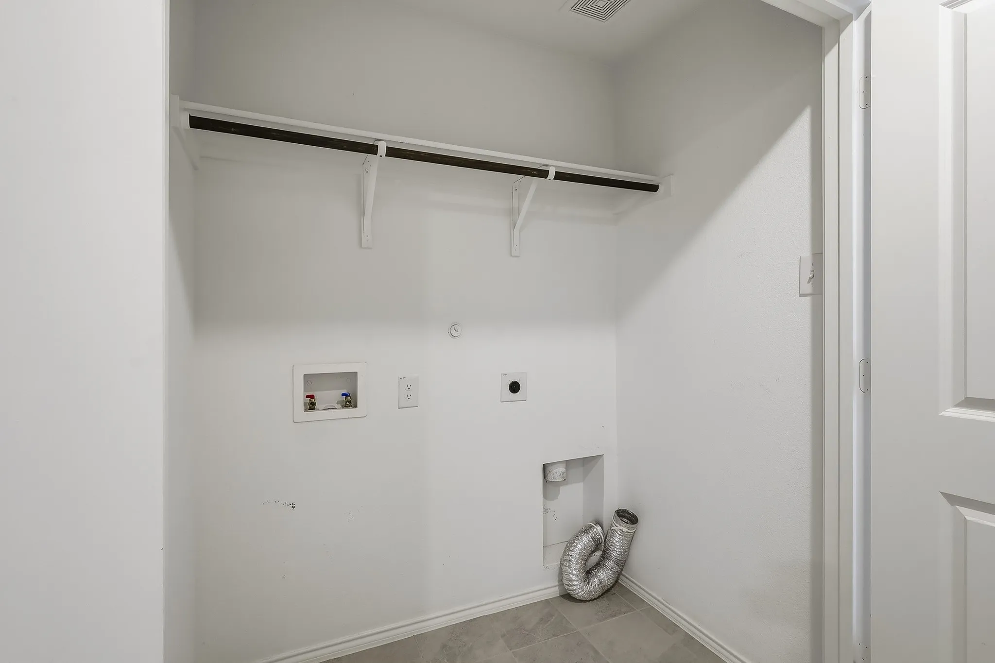 Laundry area with tile flooring, wall-mounted shelving, and washer/dryer hookups