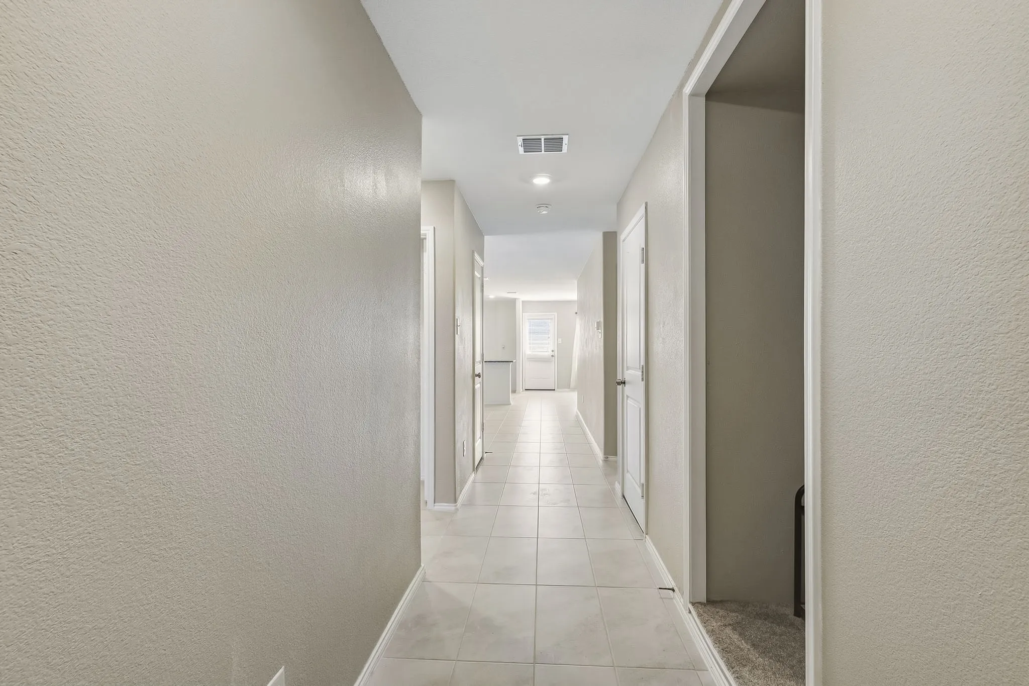 Hallway featuring tile flooring, neutral wall tones, recessed lighting, and white paneled doors