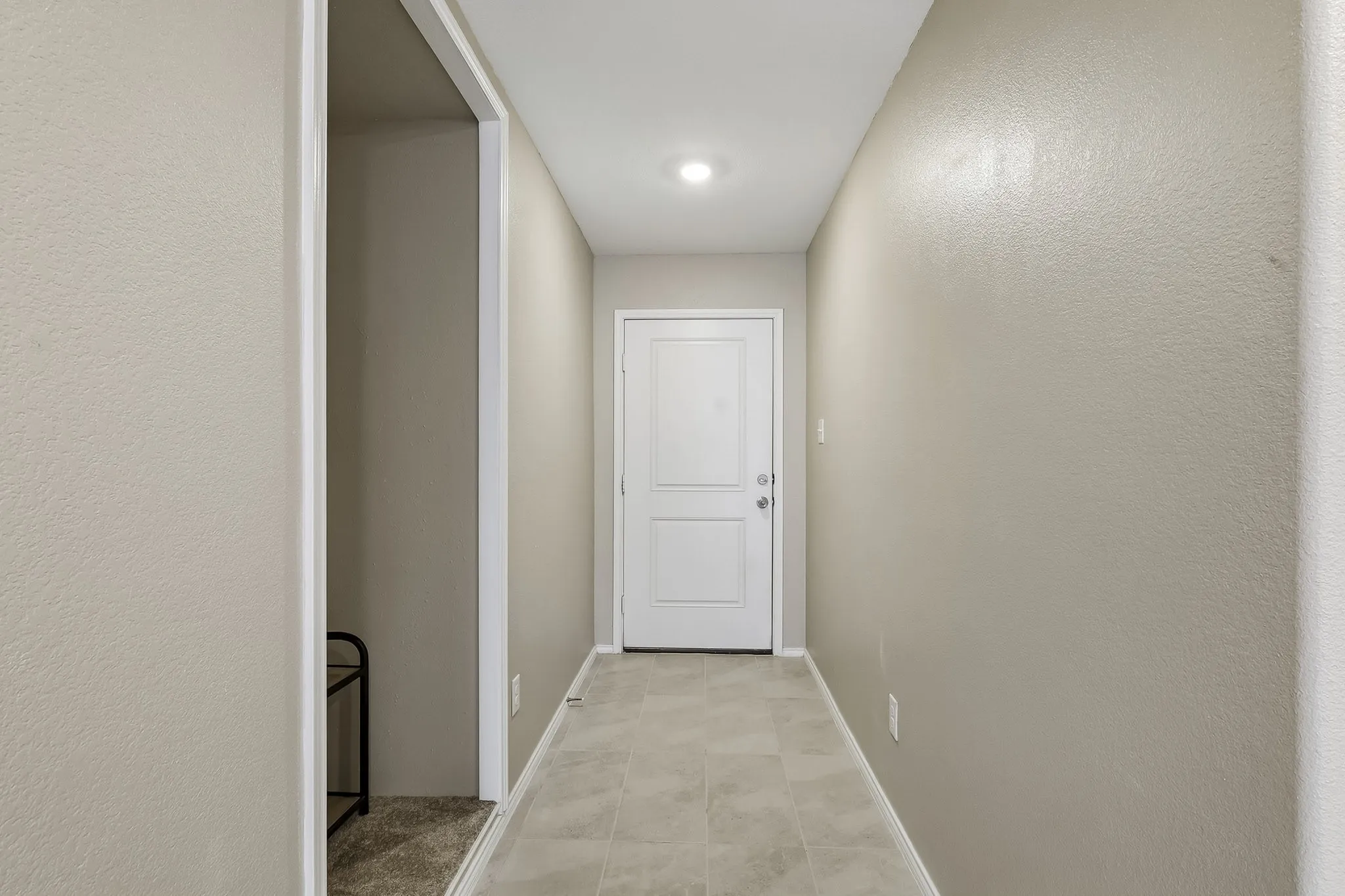 Hallway with neutral tone walls, white trim, recessed lighting, and tile flooring