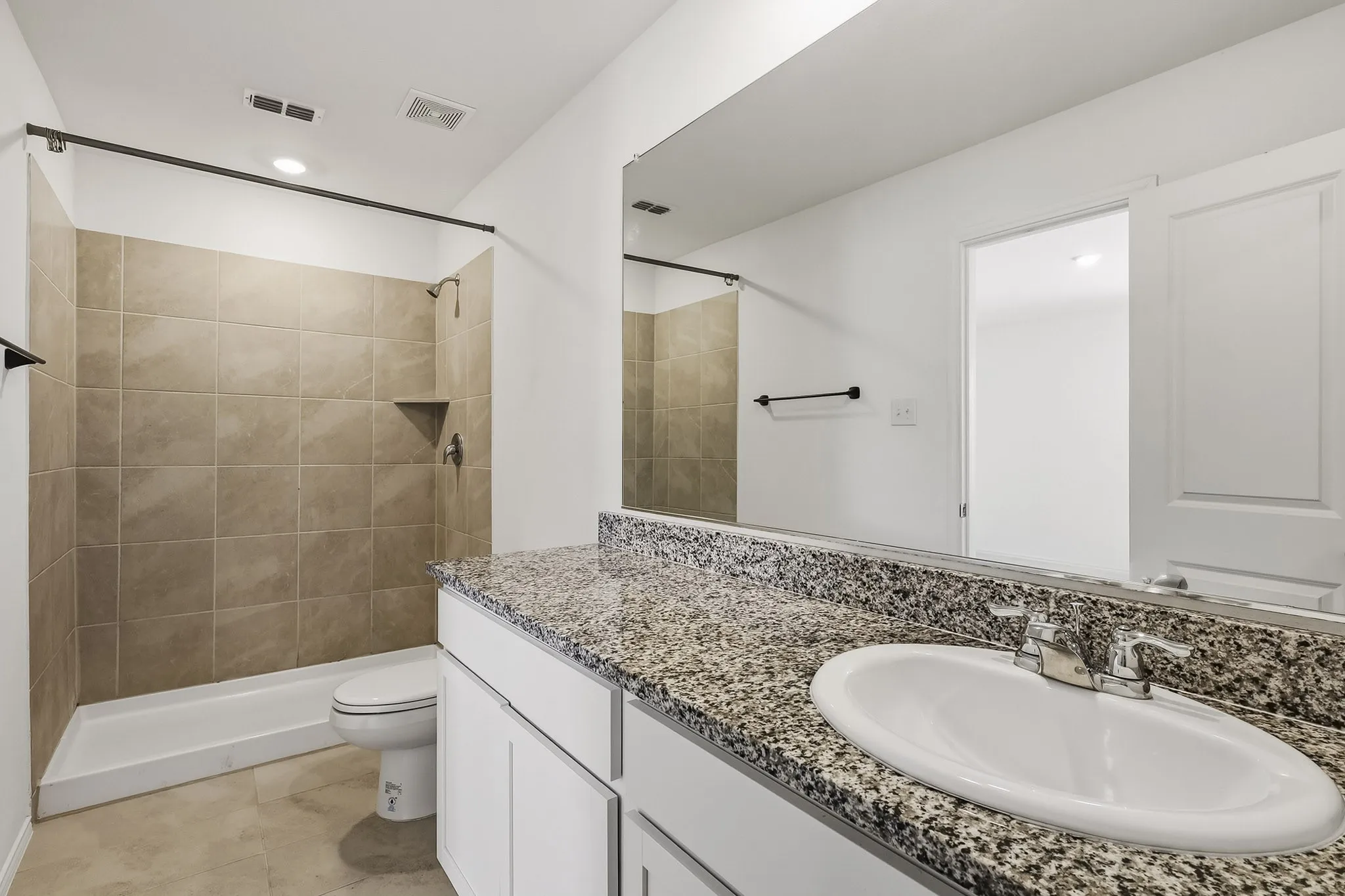 Bathroom featuring a granite countertop vanity, integrated sink, tiled shower, and a recessed shower niche